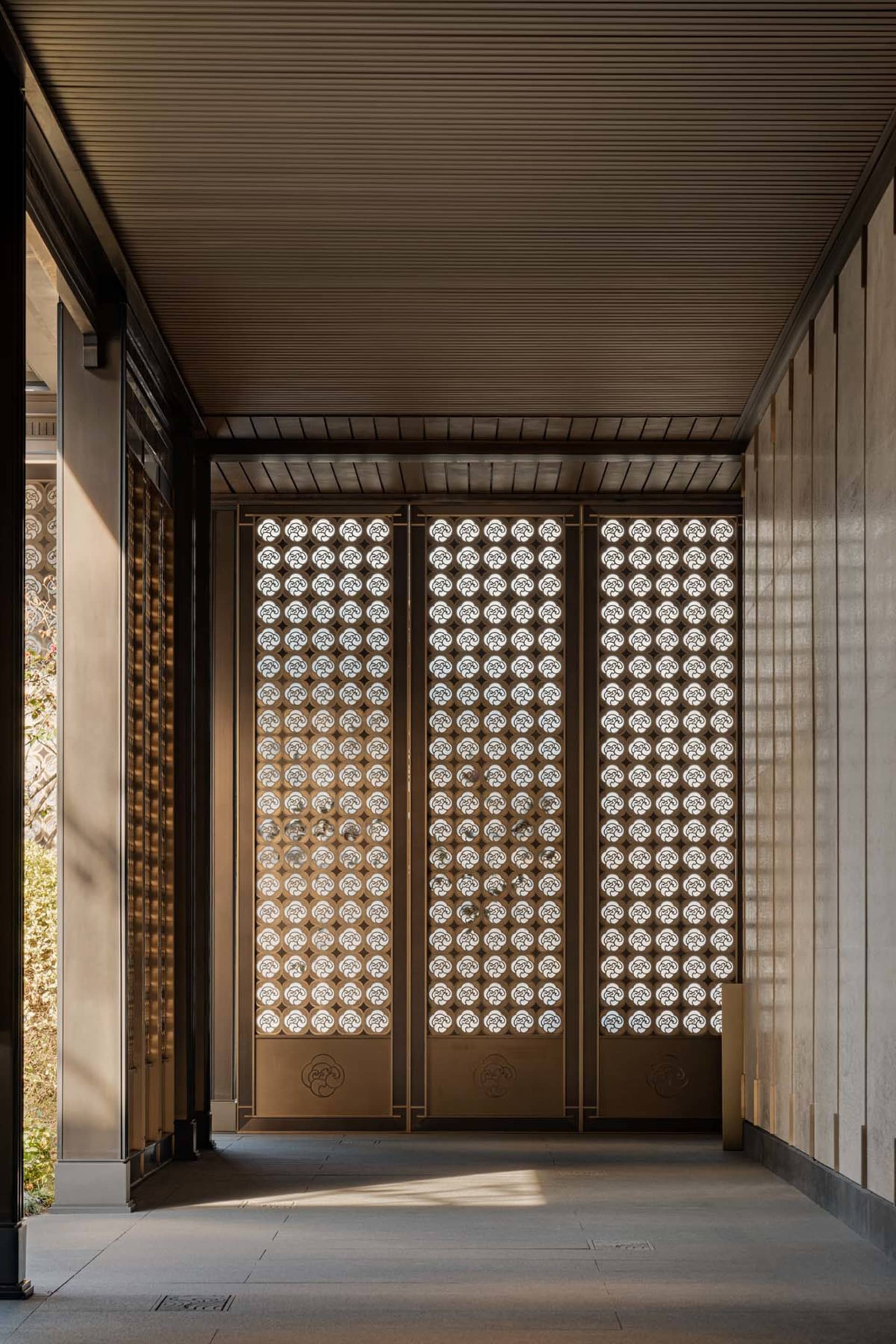 An entrance with a minimalist design featuring metal patterns and a wooden floor.