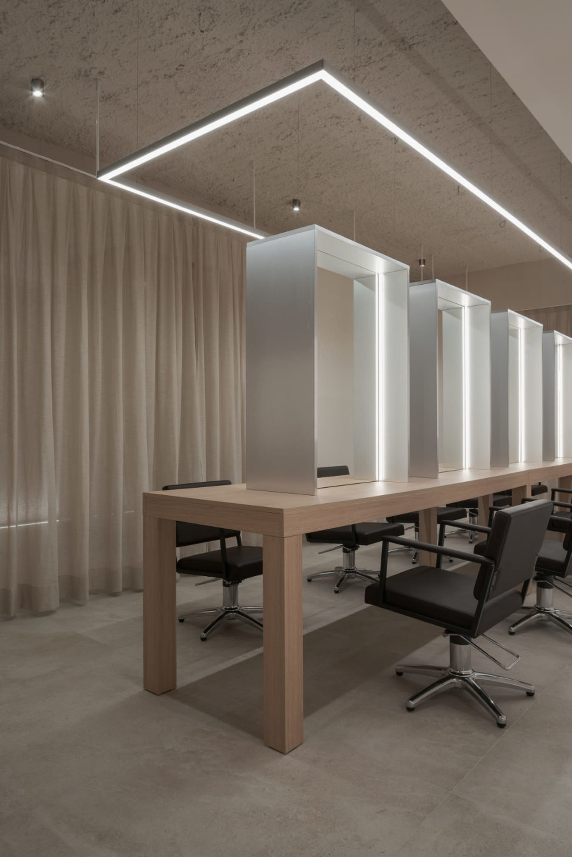 A modern hair salon with sleek, white stations and illuminated mirrors.