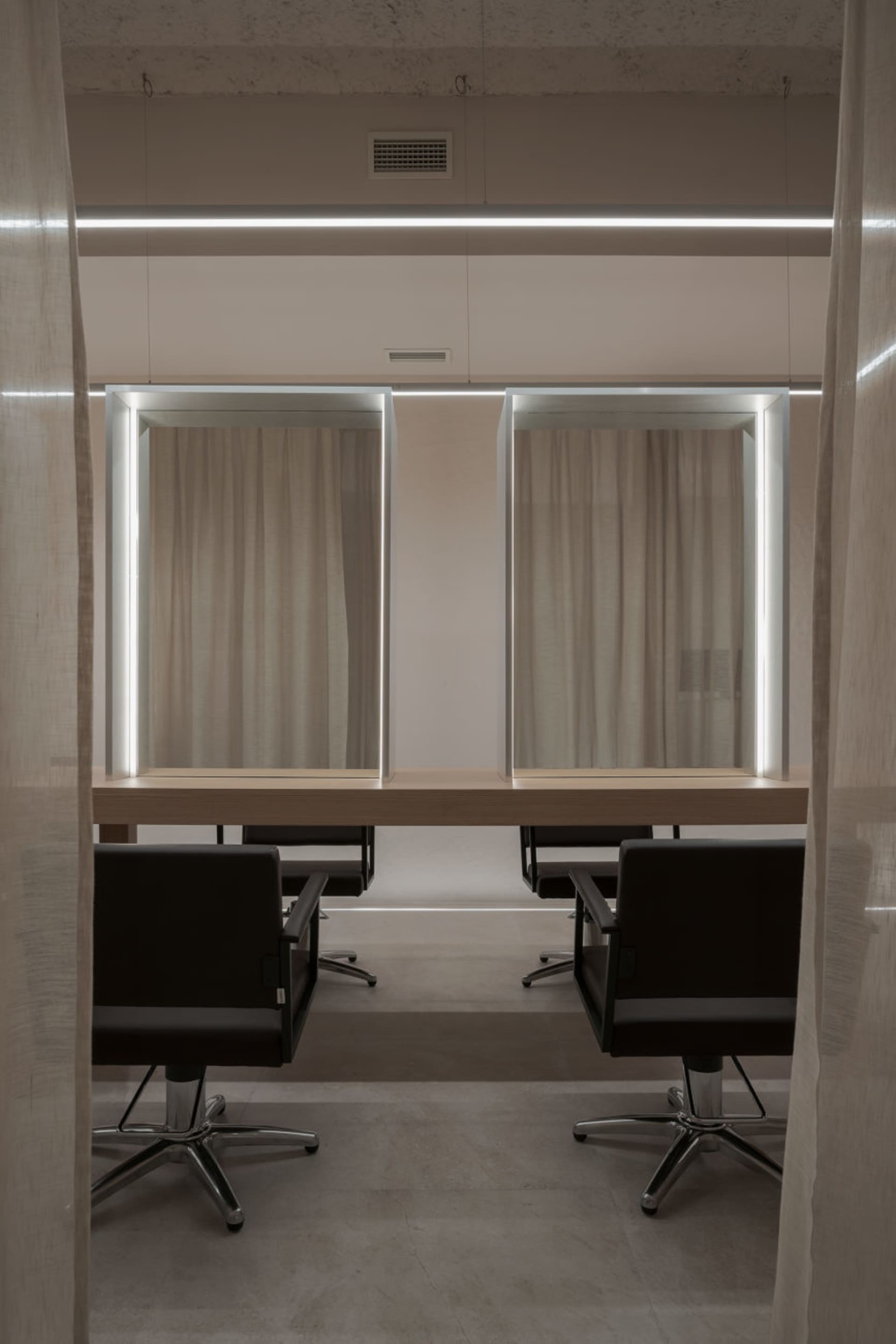 A modern hair salon station featuring a wooden countertop and glass panels.