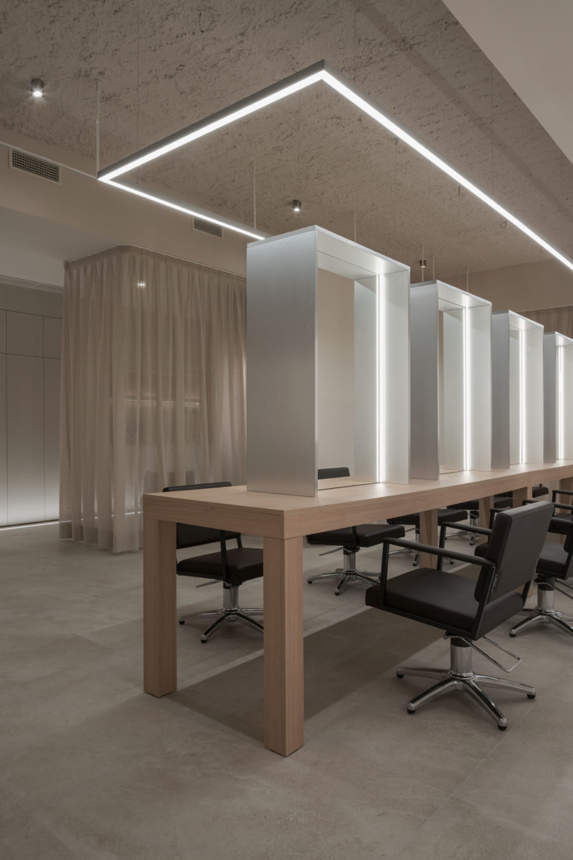 A modern salon interior with a wooden table and black chairs.