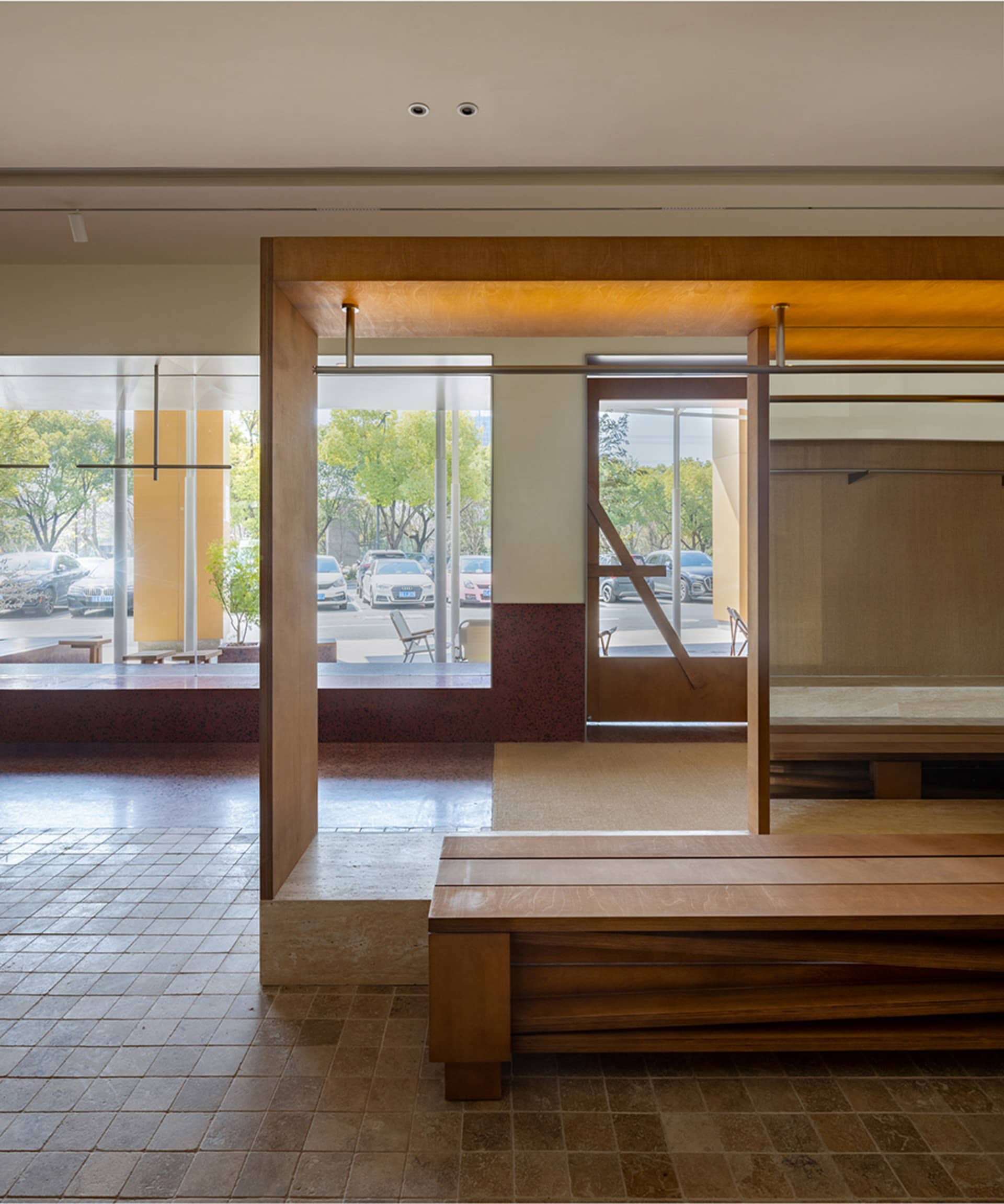 A modern lobby interior featuring wooden benches and glass partitions.
