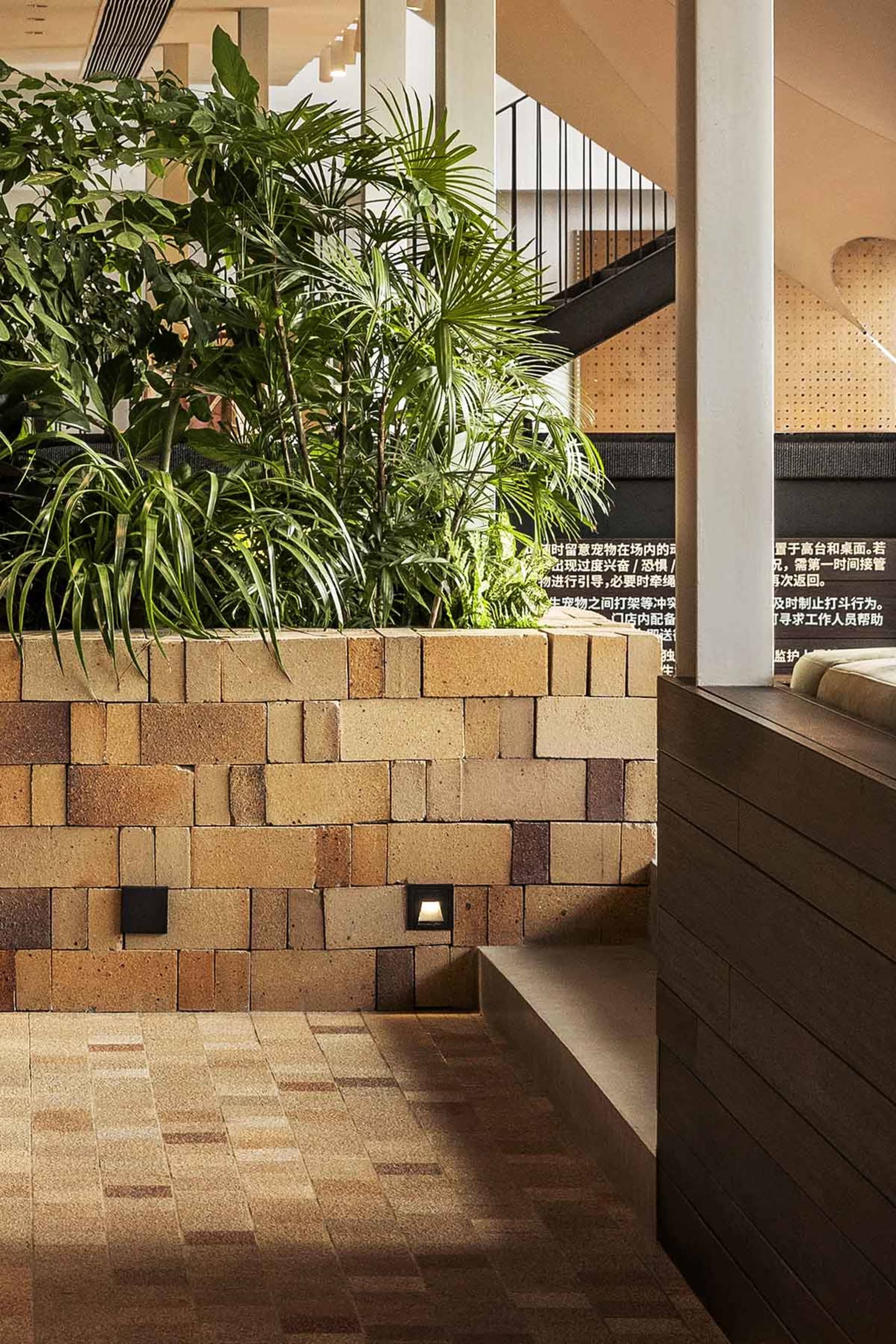 Modern retail space with brick flooring, plants, and wooden seating.