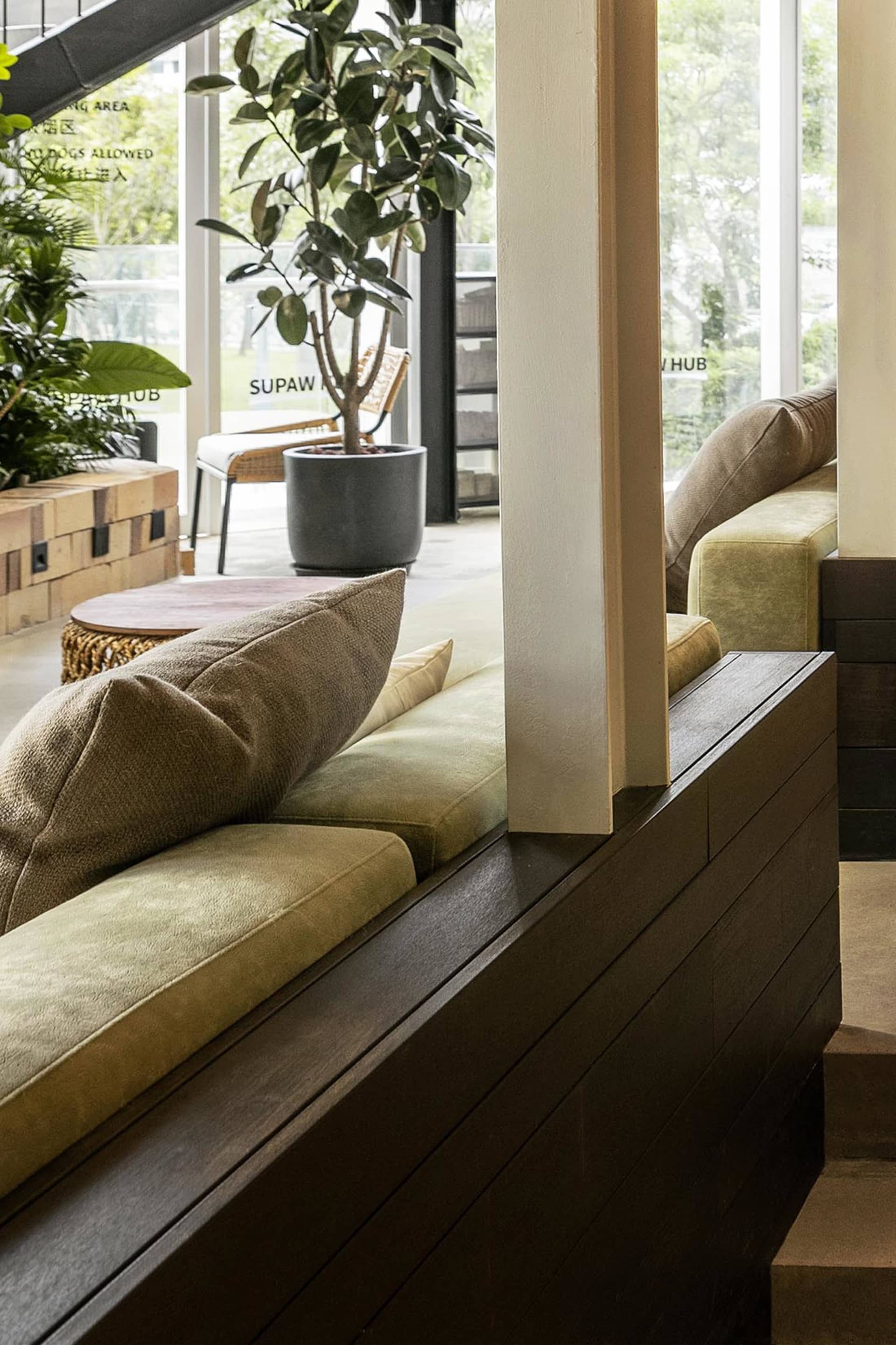 Modern living room with wooden furniture and potted plants, featuring soft lighting and cozy seating area.
