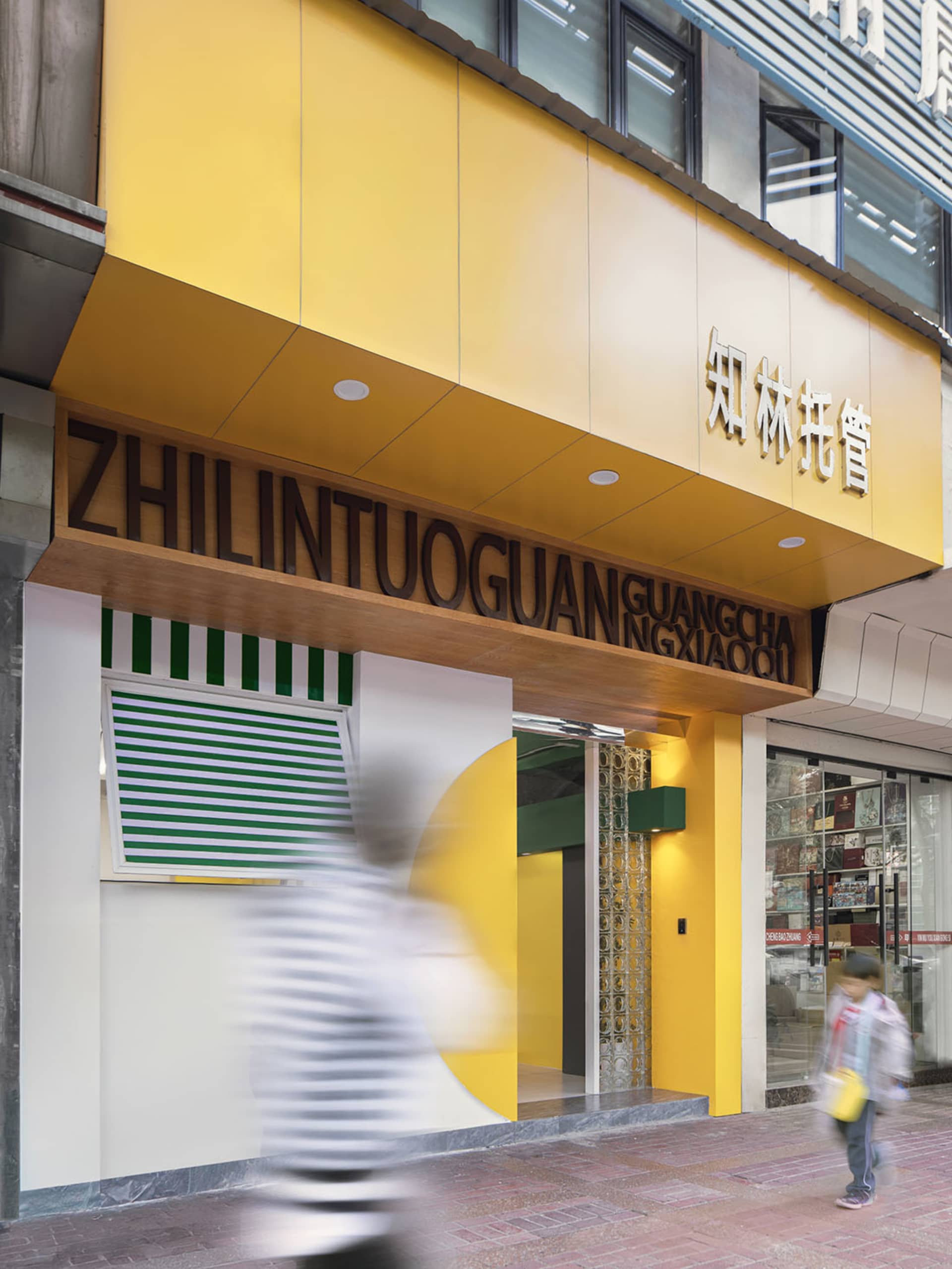 充滿活力的街邊店面,搭配黃色金屬框架與綠白條紋門面。