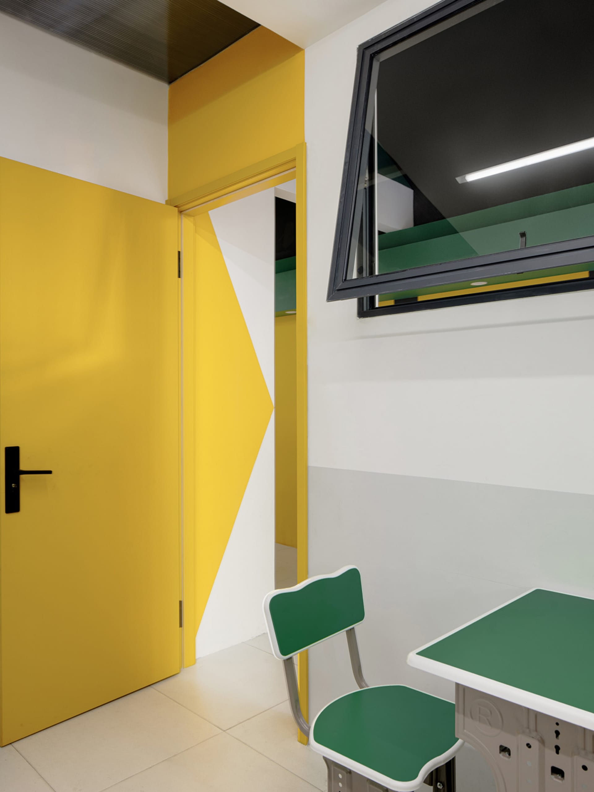 Modern educational space featuring yellow door and green furniture.