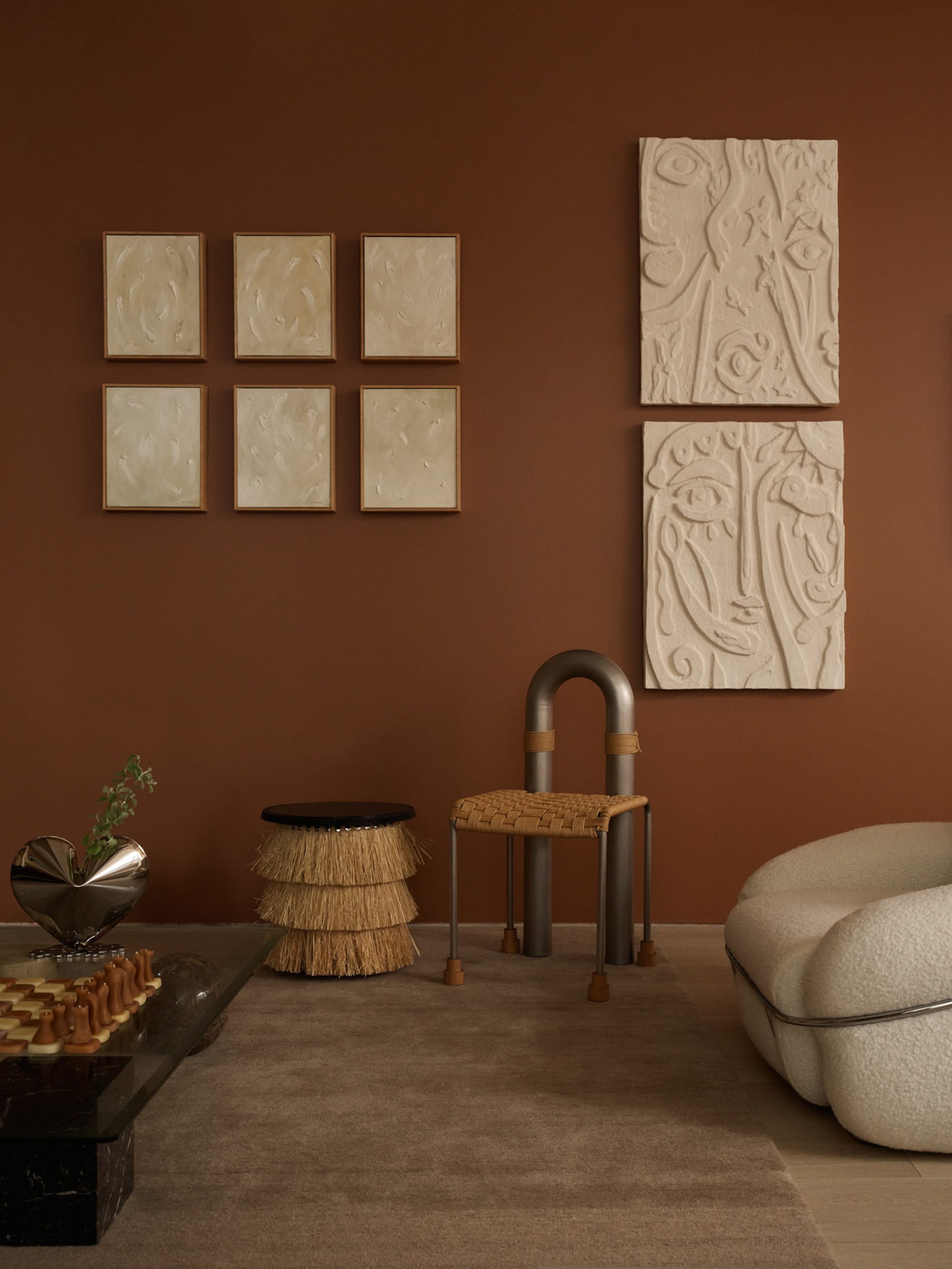 A modern living room with abstract art on the wall, featuring a glass coffee table, a beige upholstered chair, and various sc