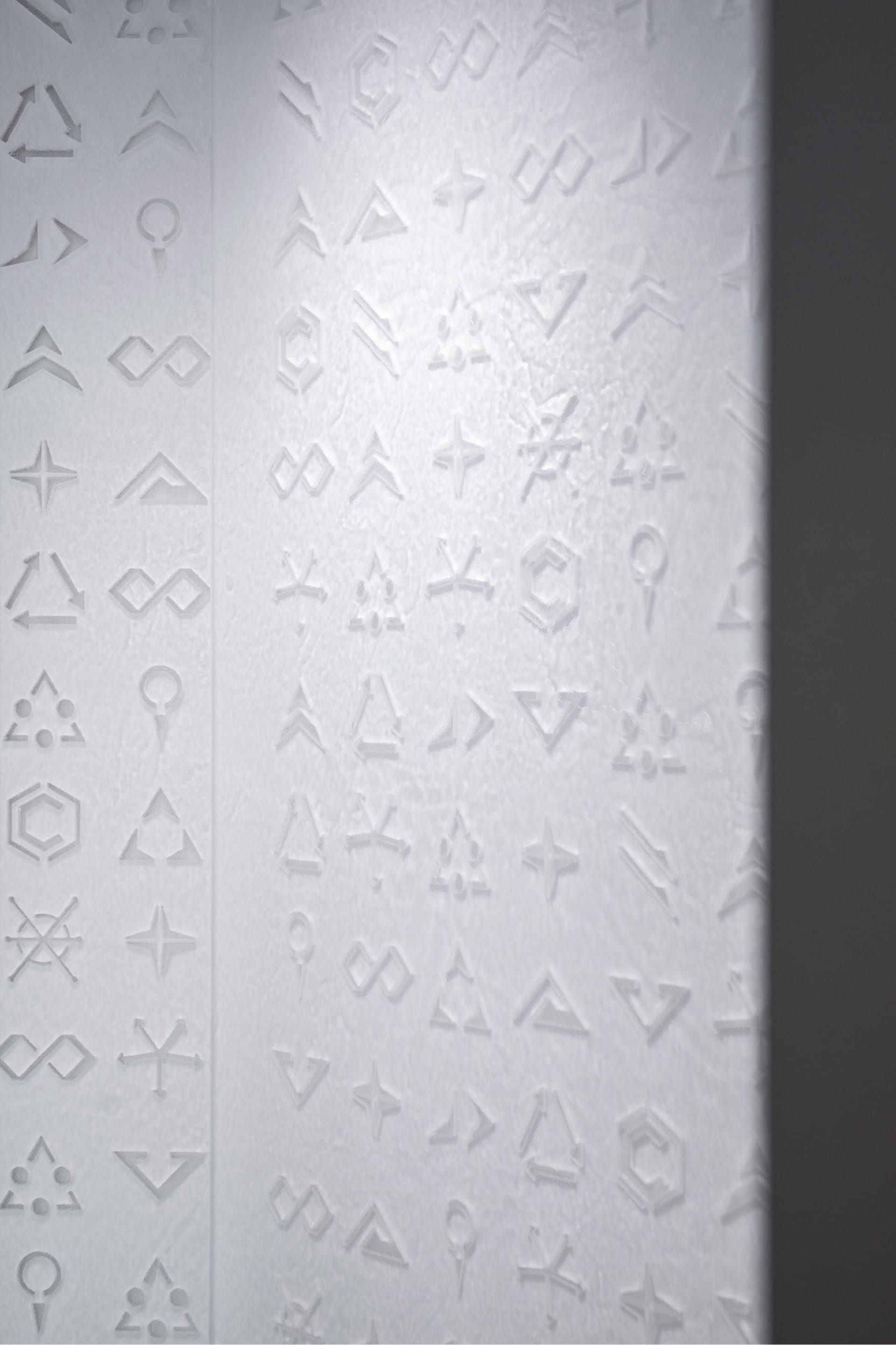 Embossed symbols on a textured, white paper surface.