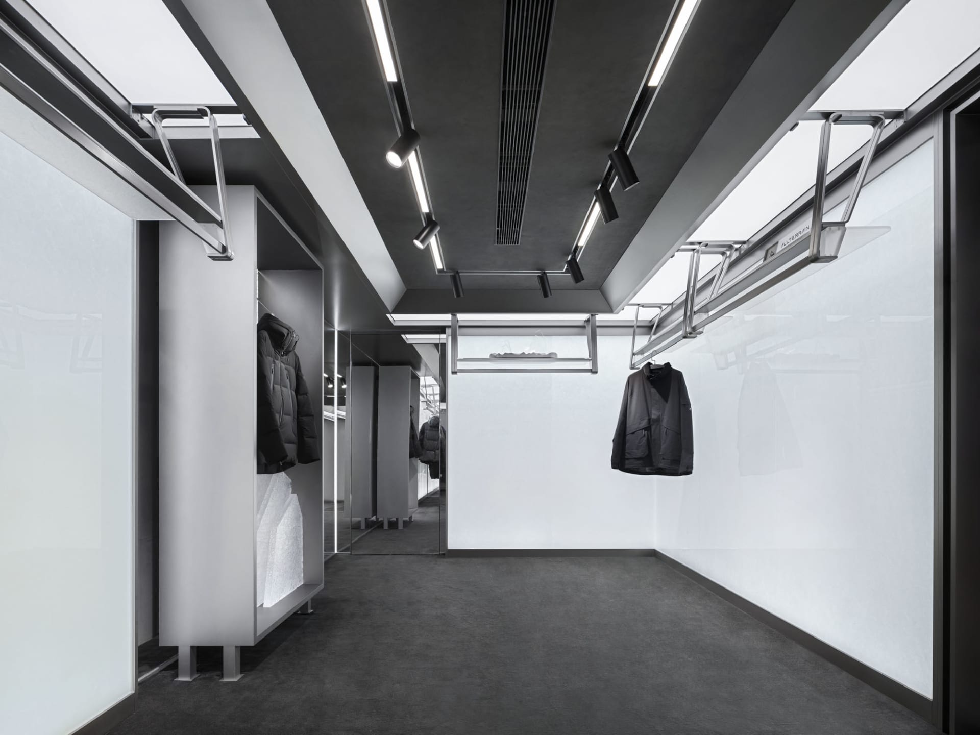 A minimalist showroom with metal structures, large glass panels, and concrete elements.