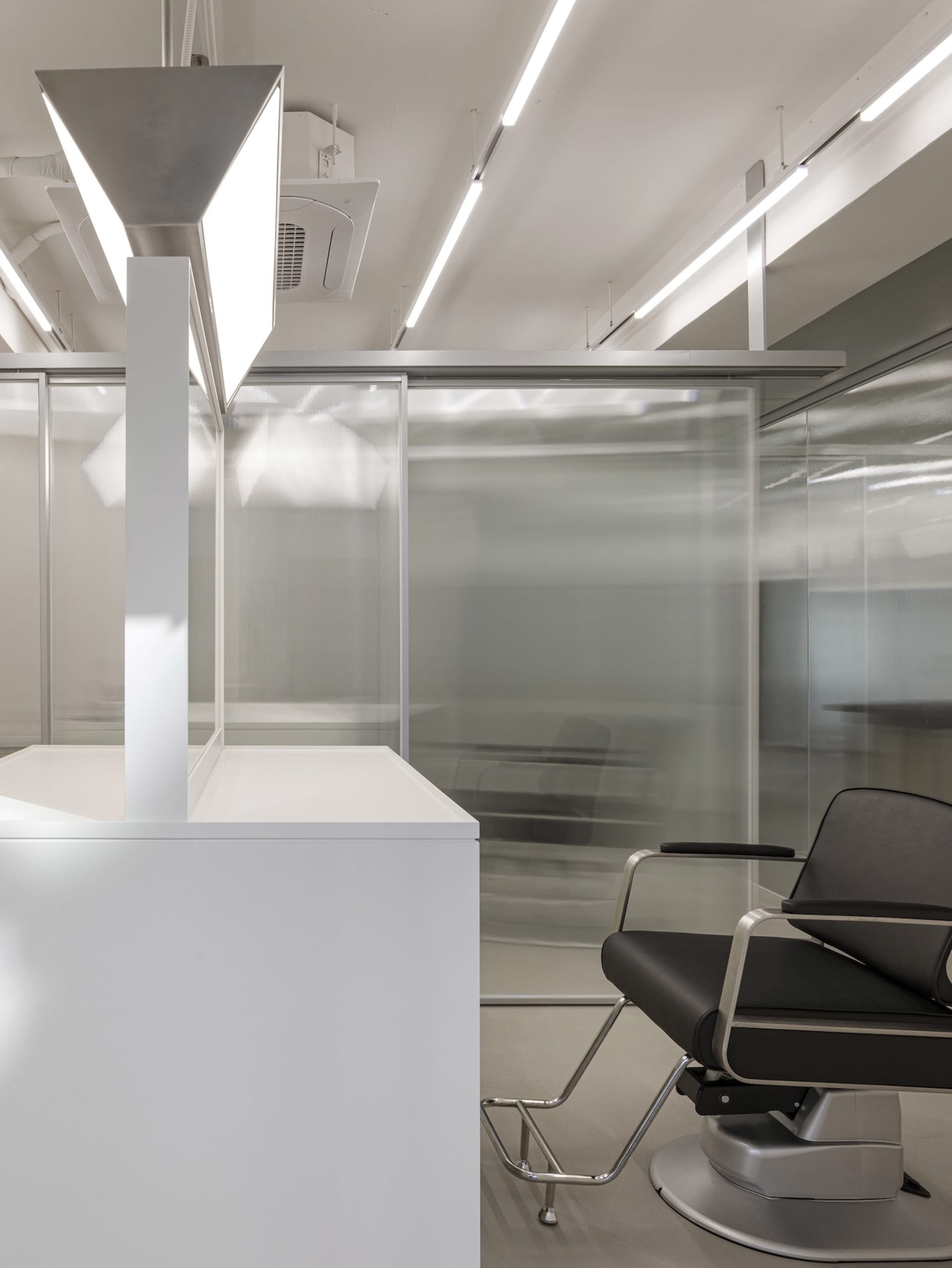 Contemporary office space featuring a sleek, modern design with glass walls and white surfaces.