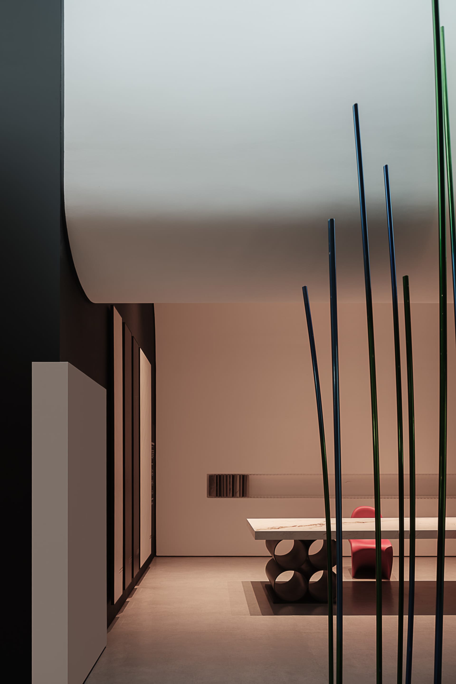 Minimalist modern dining room featuring sleek marble table and concrete chairs under a white ceiling.