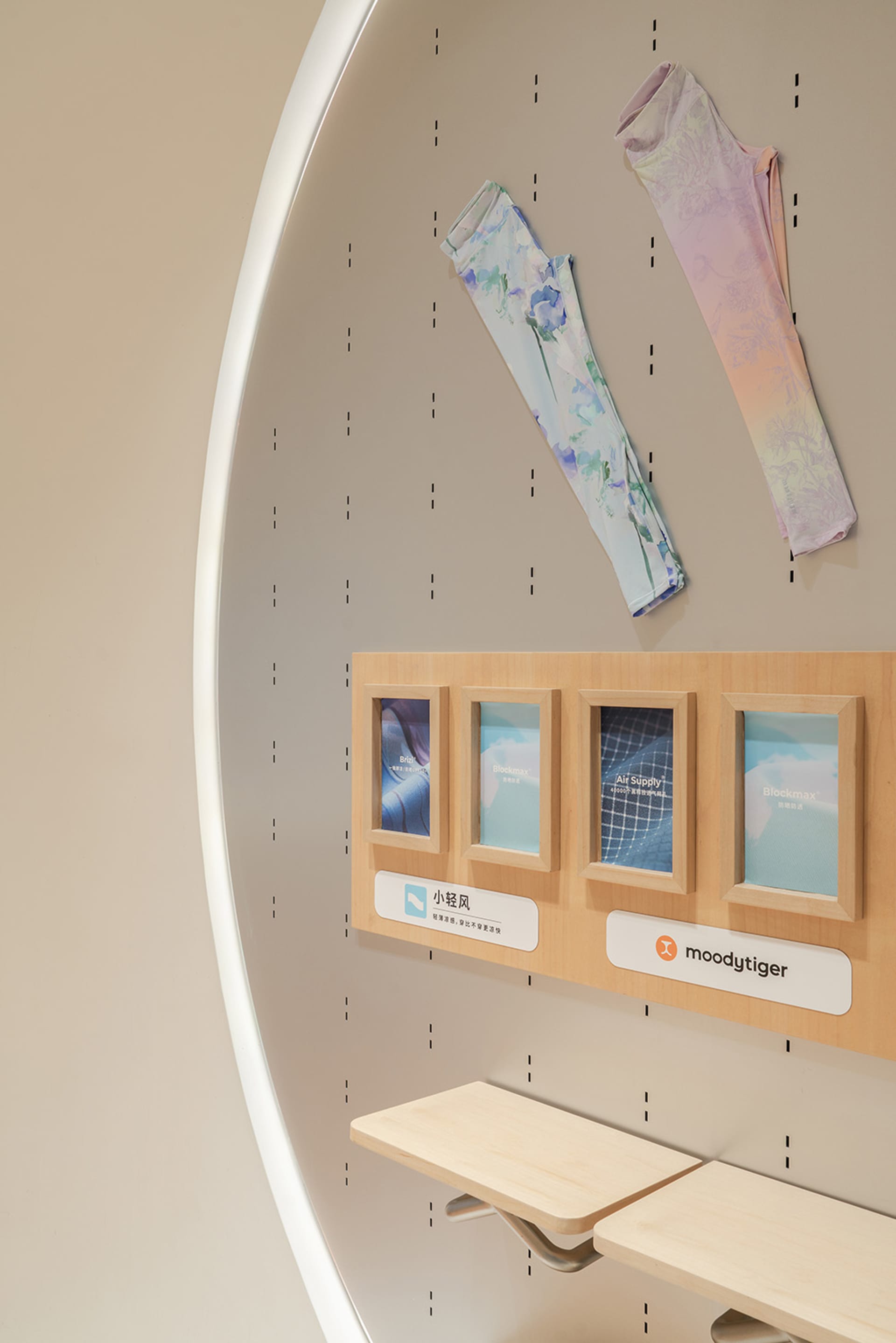 A modern retail interior displaying accessories with a wooden display board and two hanging arm sleeves.
