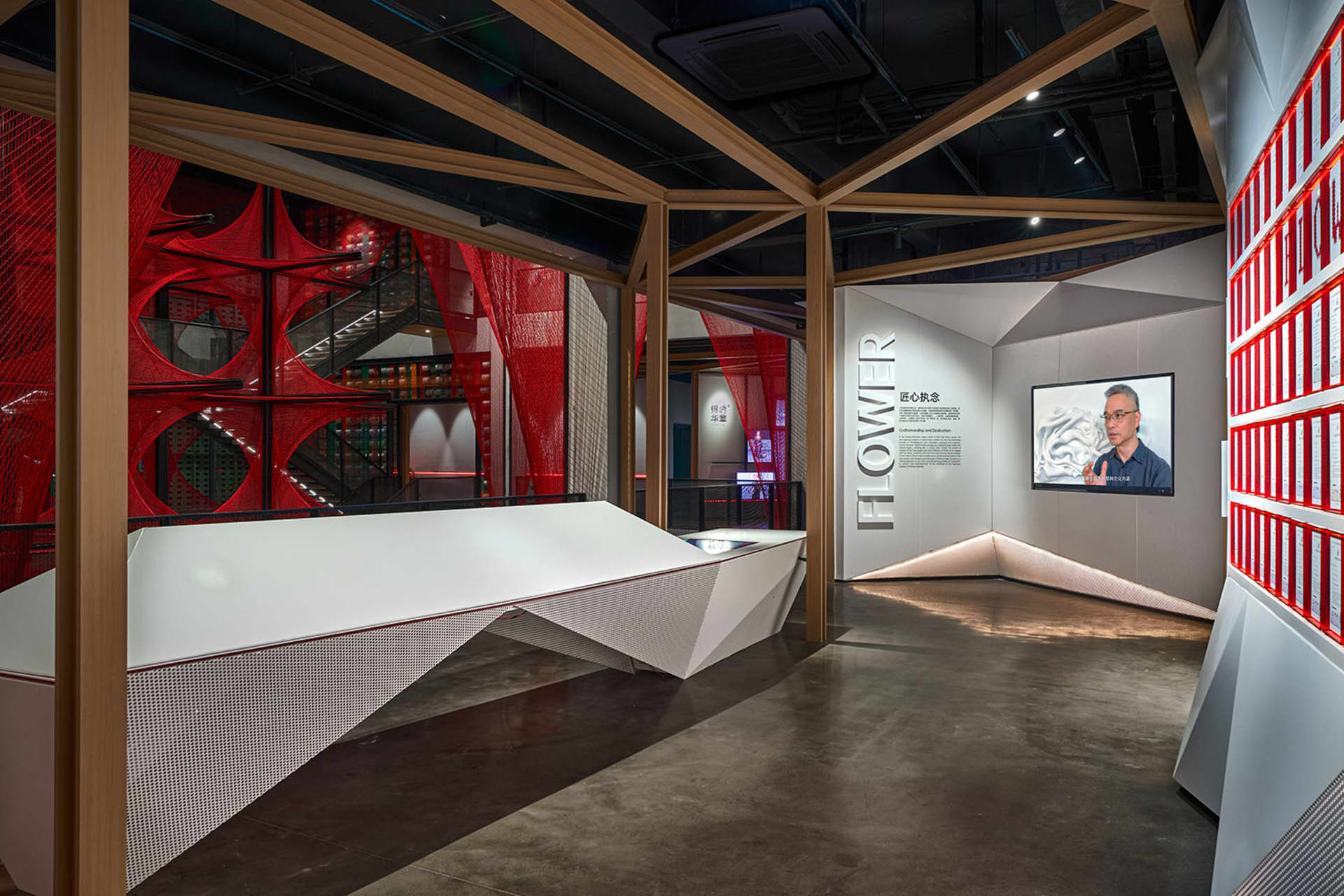 A modern exhibition hall with a red netting structure and concrete flooring.
