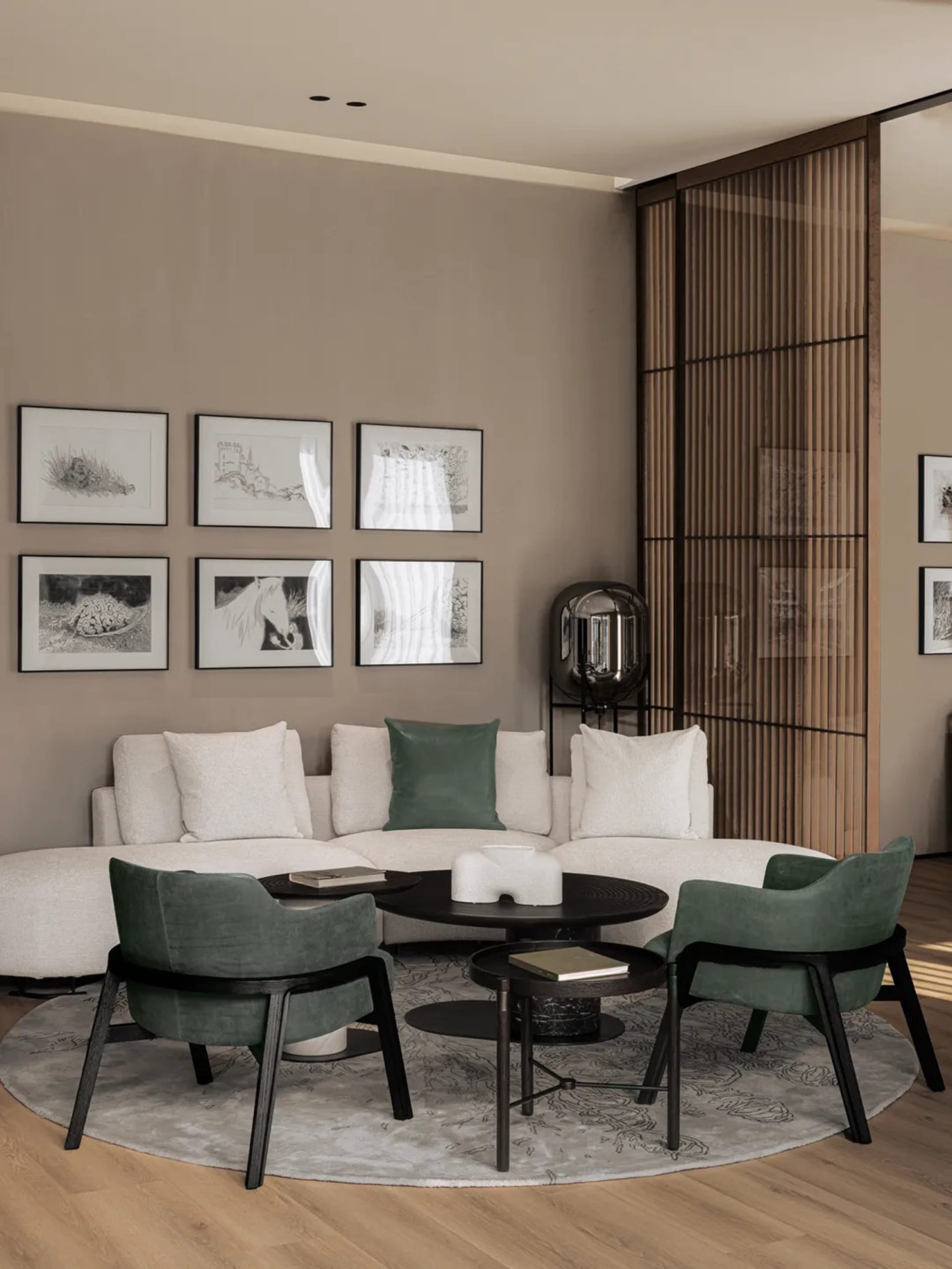 A modern minimalist living room featuring a white L-shaped sofa, green accent chairs, and a round coffee table with a minimal