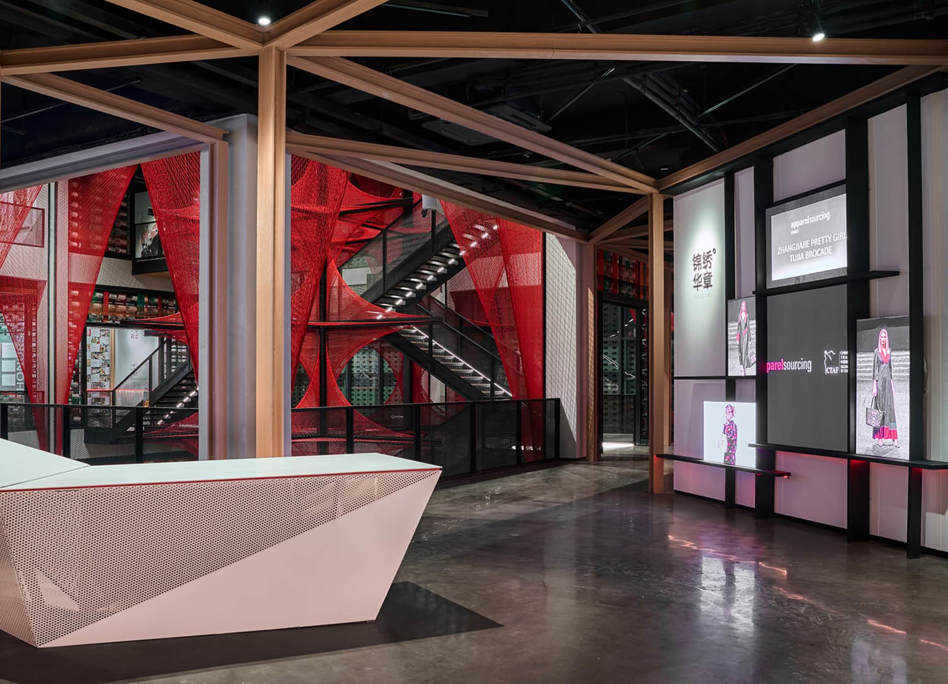 An interior of a modern retail store with red netting and black steel architectural elements.