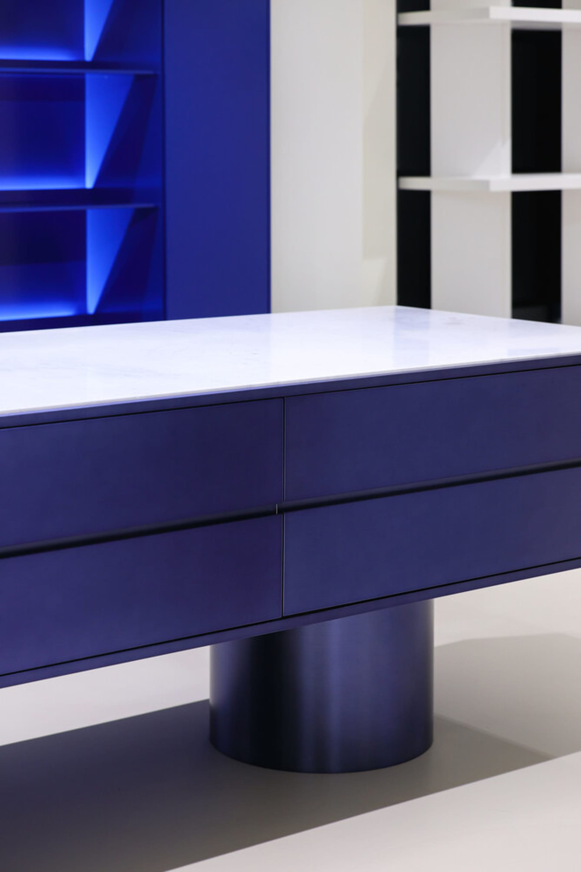 A minimalist furniture piece with a metal base and a marble top.