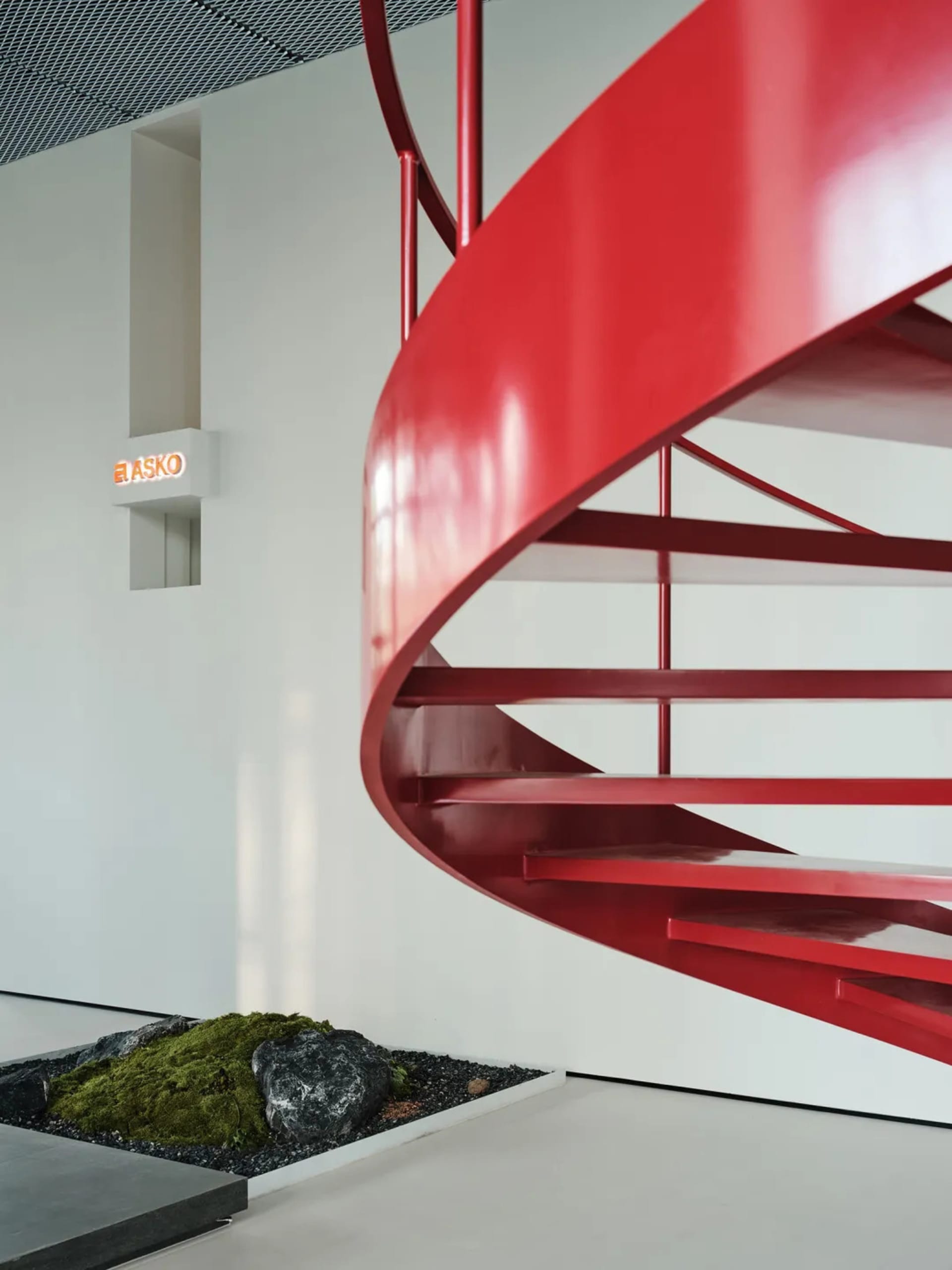 A modern red spiral staircase within an industrial-style interior space.