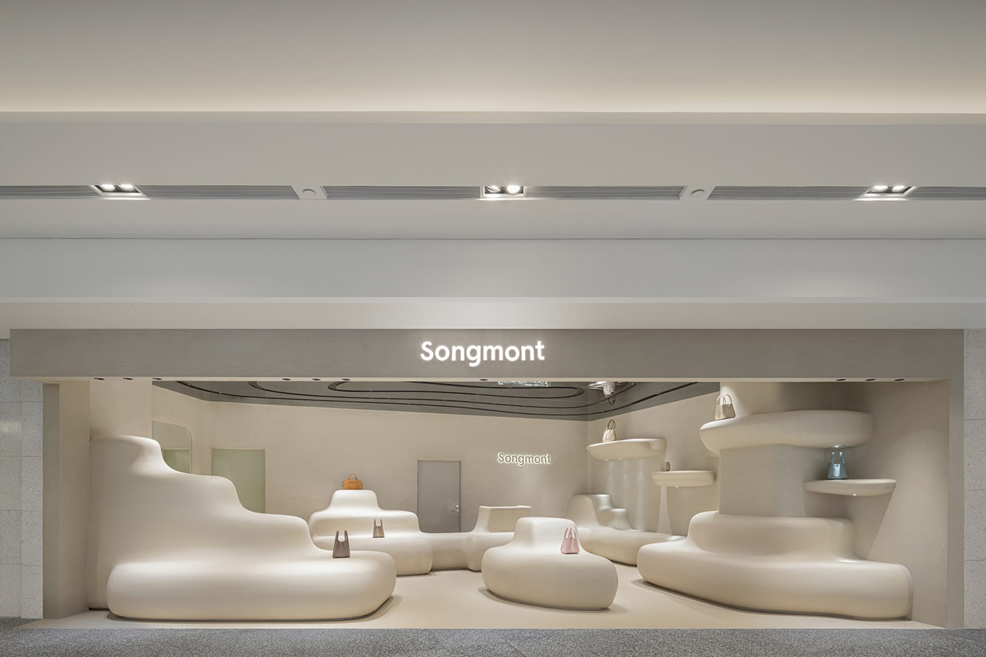 Modern minimalist retail storefront with white, curved furniture and signage for Songmont.