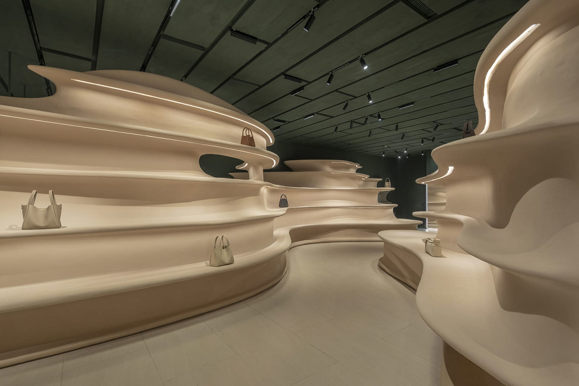 Modern retail interior featuring a sculptural plaster storefront display with handbags.