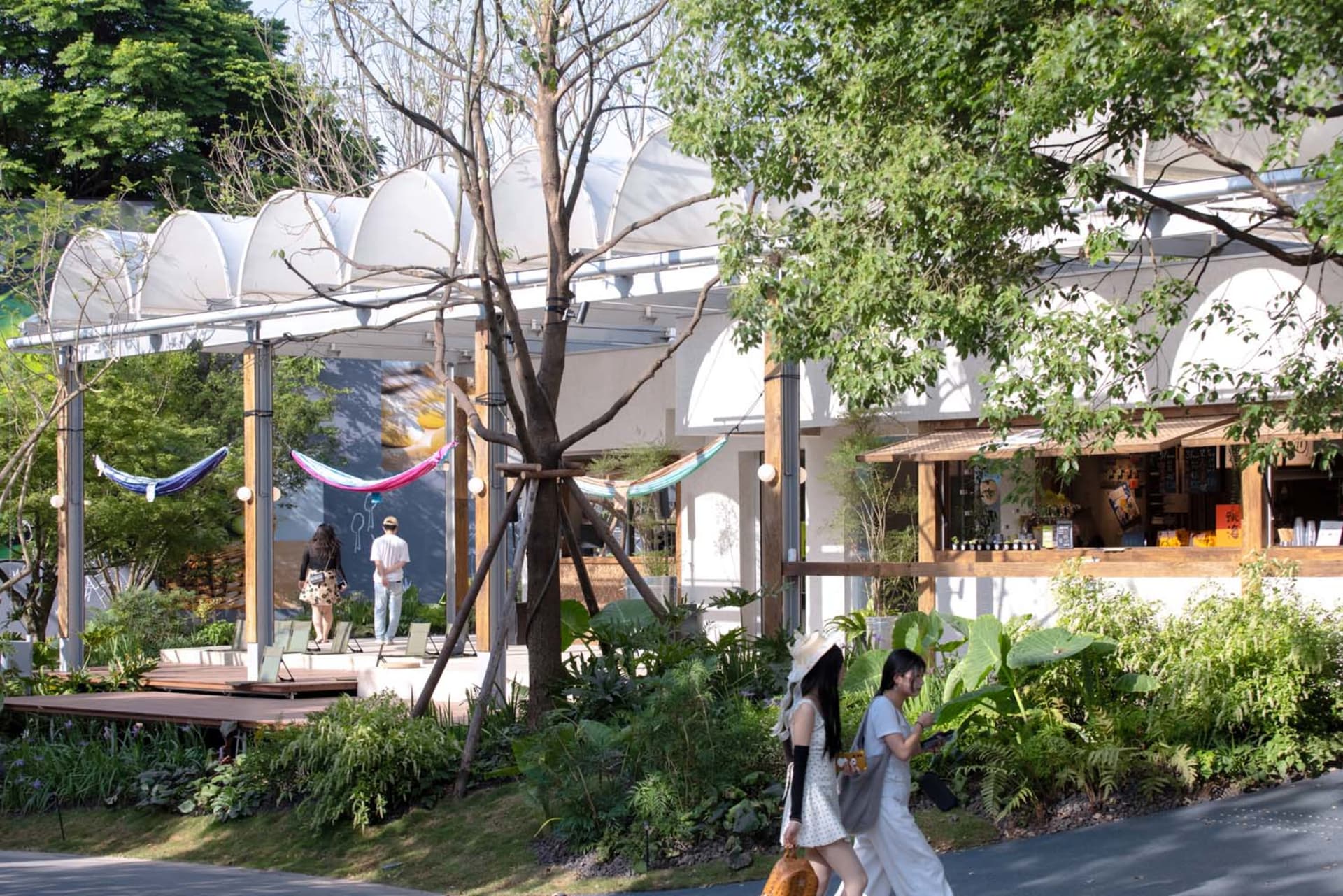 A modern garden center with a white building facade, greenery, and hammocks.