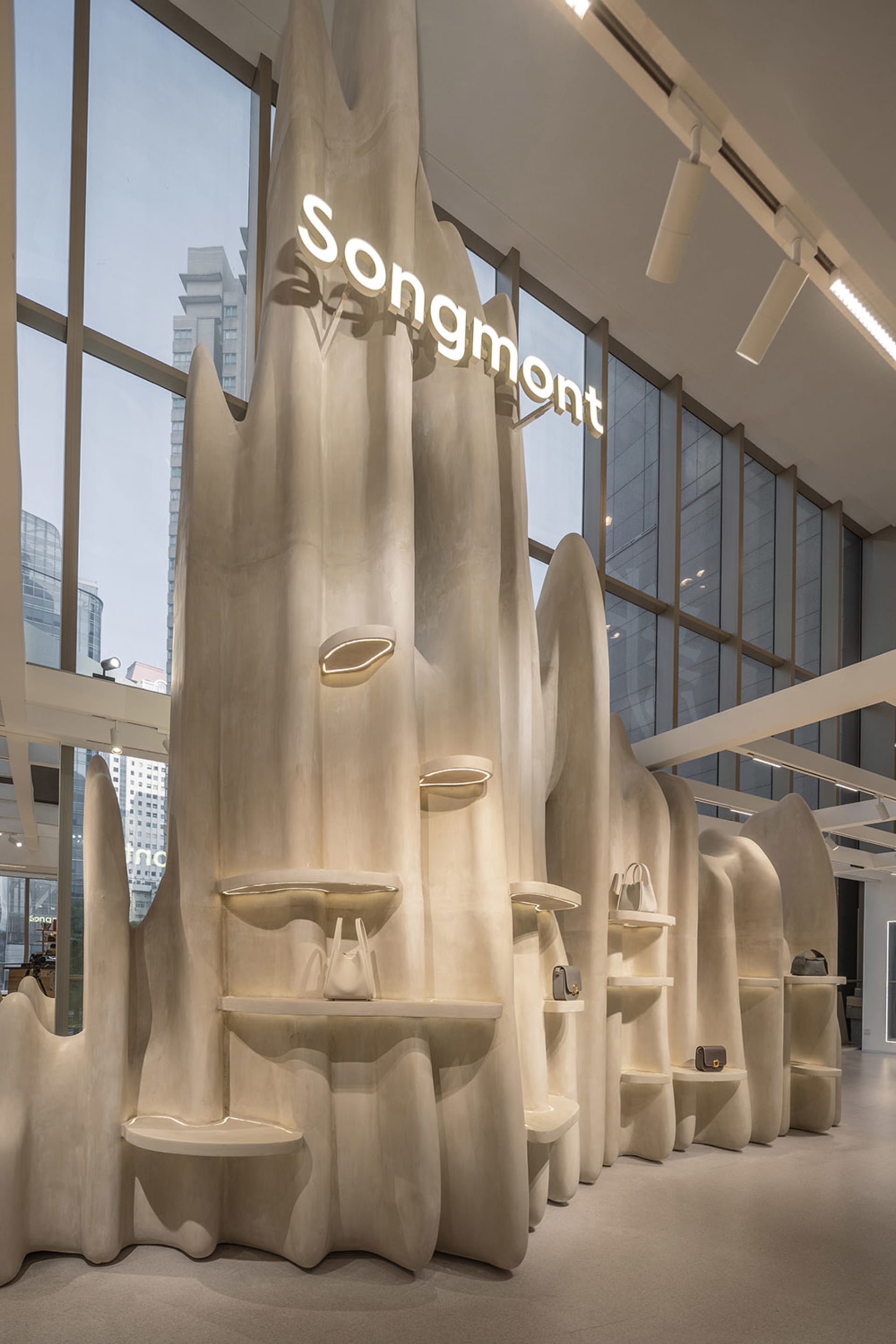 A modern retail interior featuring concrete shelves displaying handbags.