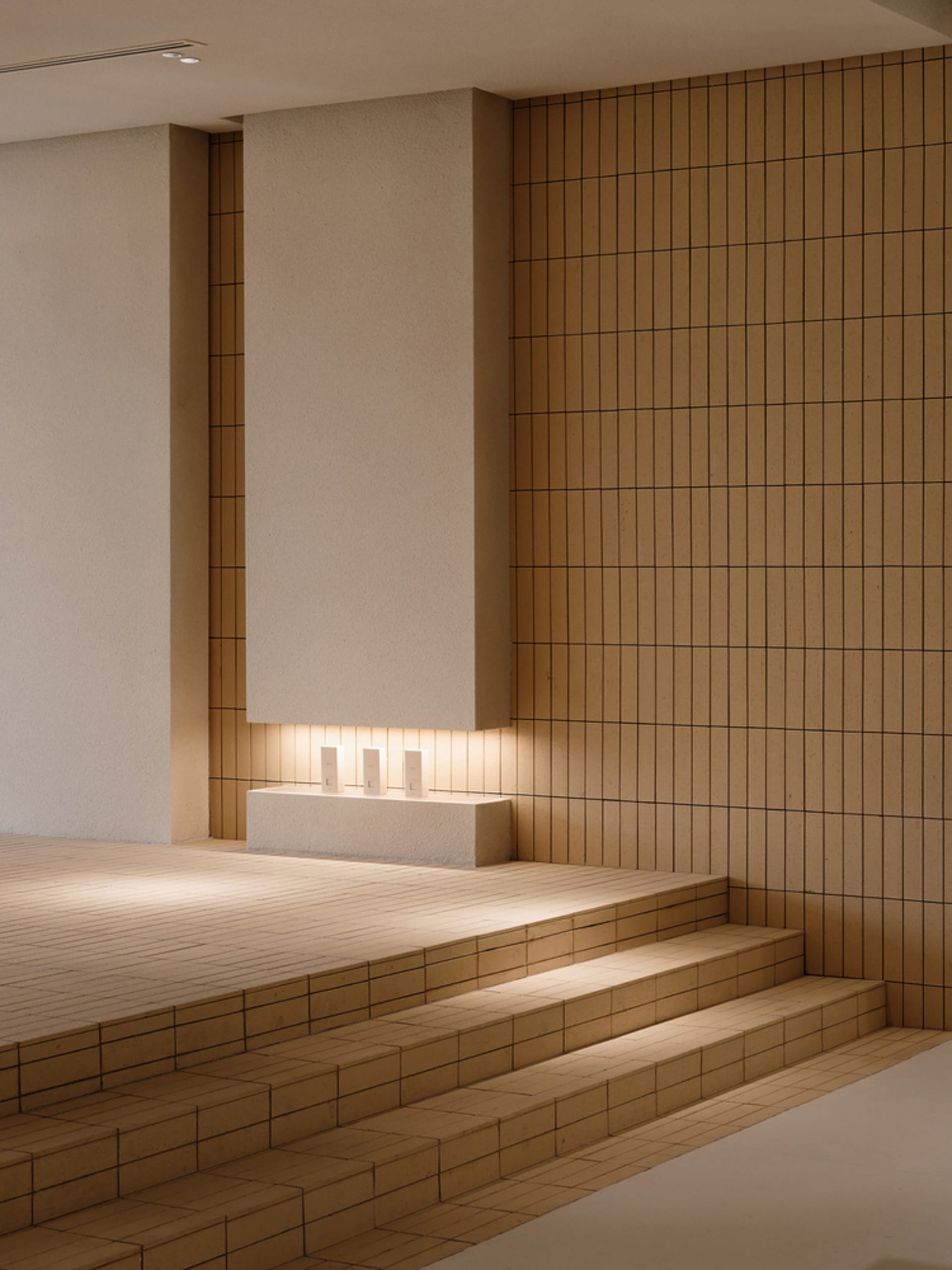 Minimalist staircase with tiled steps and a concrete wall.