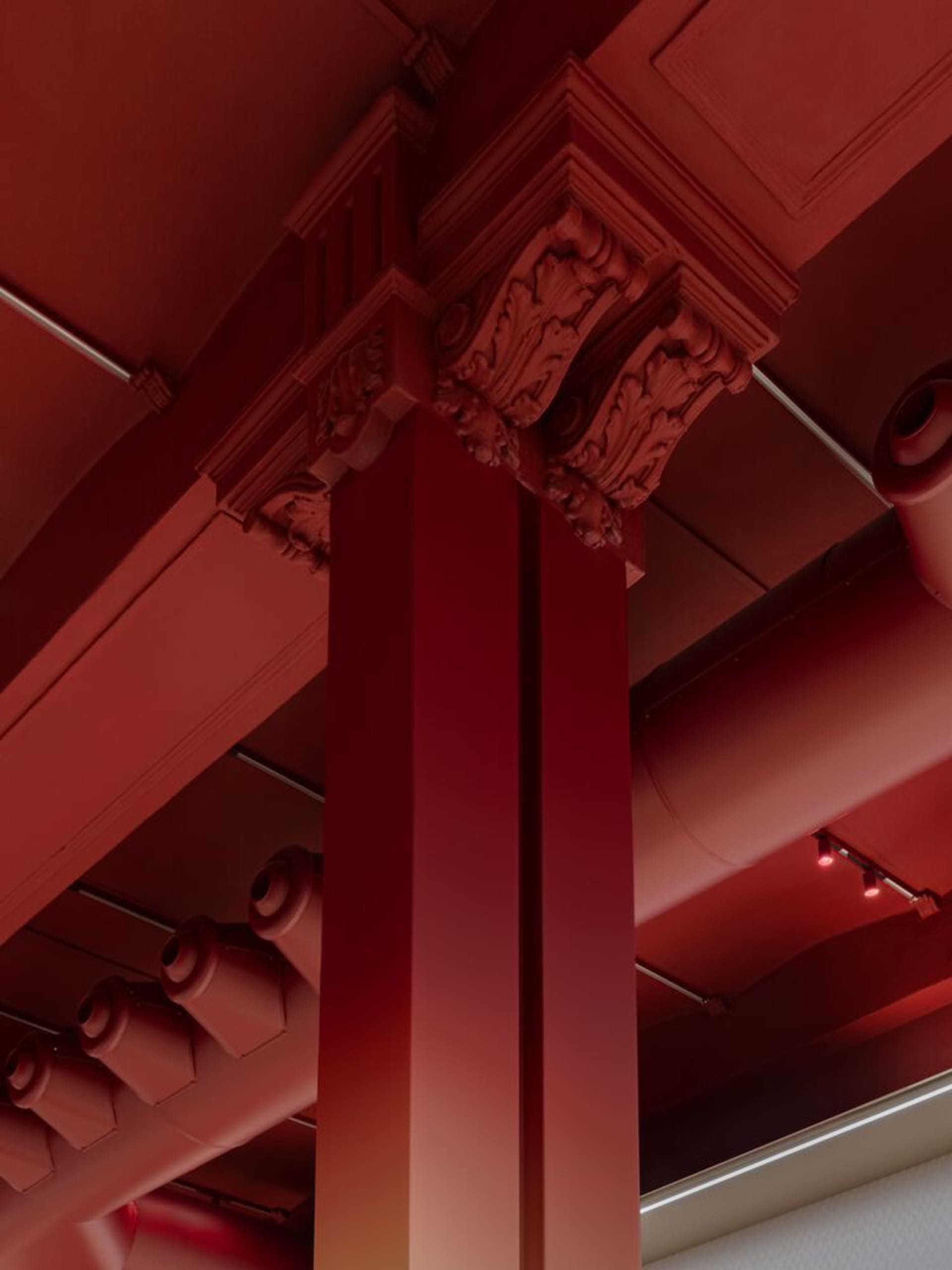 A red-painted architectural column in an interior setting, highlighting the use of vibrant color in contemporary architectura