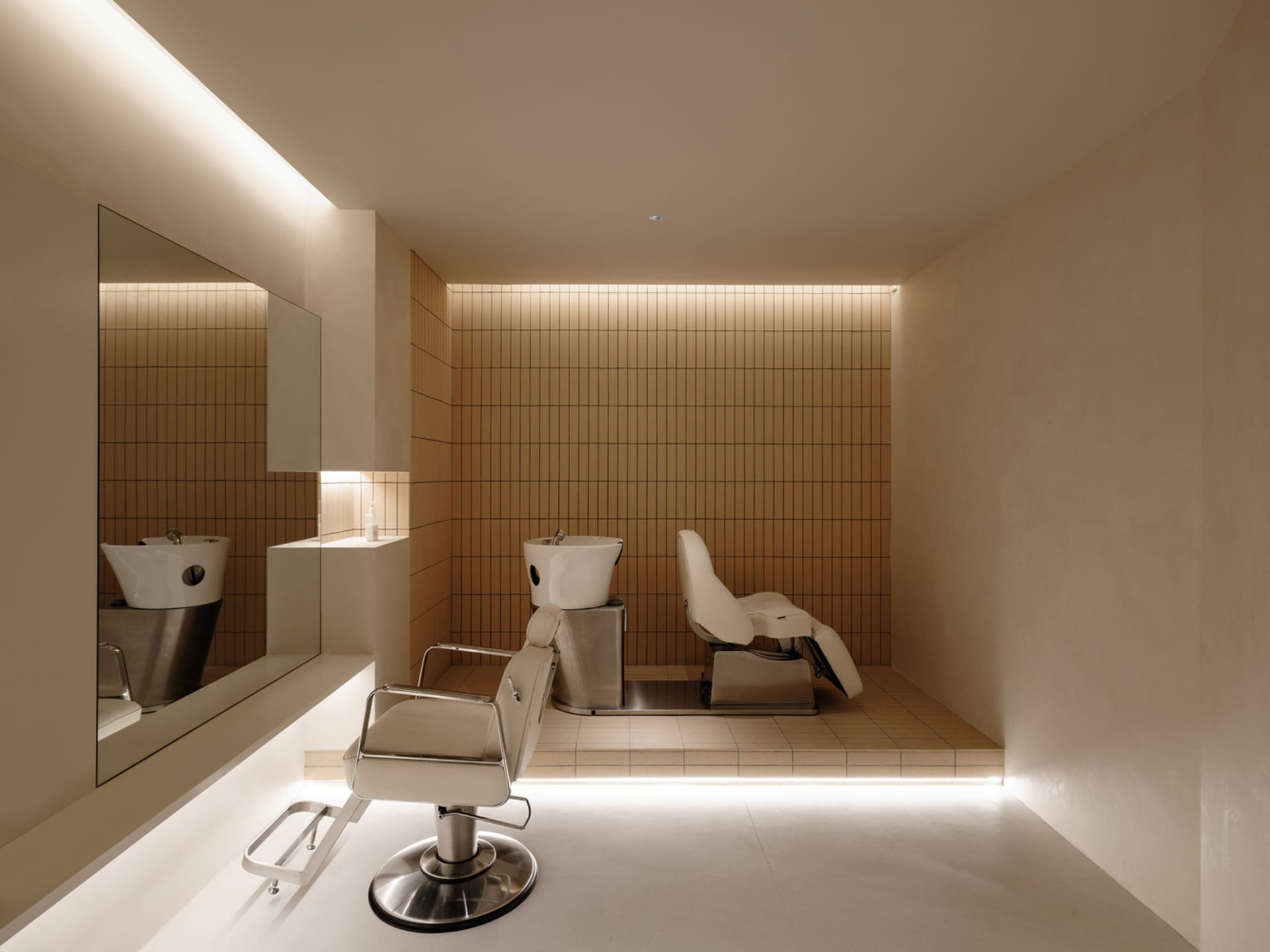 Modern salon interior with concrete tiles, minimalist white chairs, and sleek design elements.
