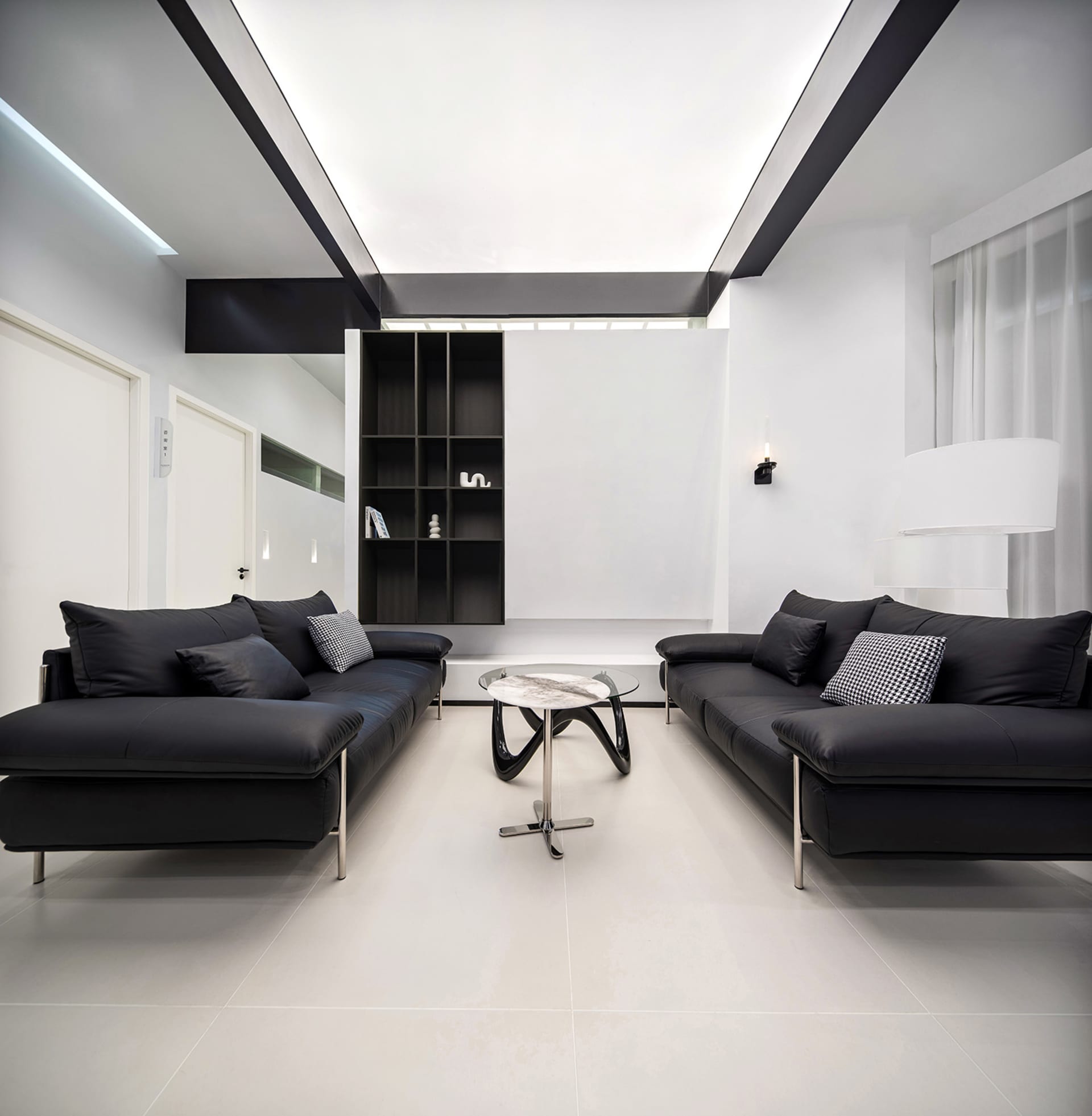 A modern living room with black leather sofas, a glass coffee table, and a minimalist glass sculpture.