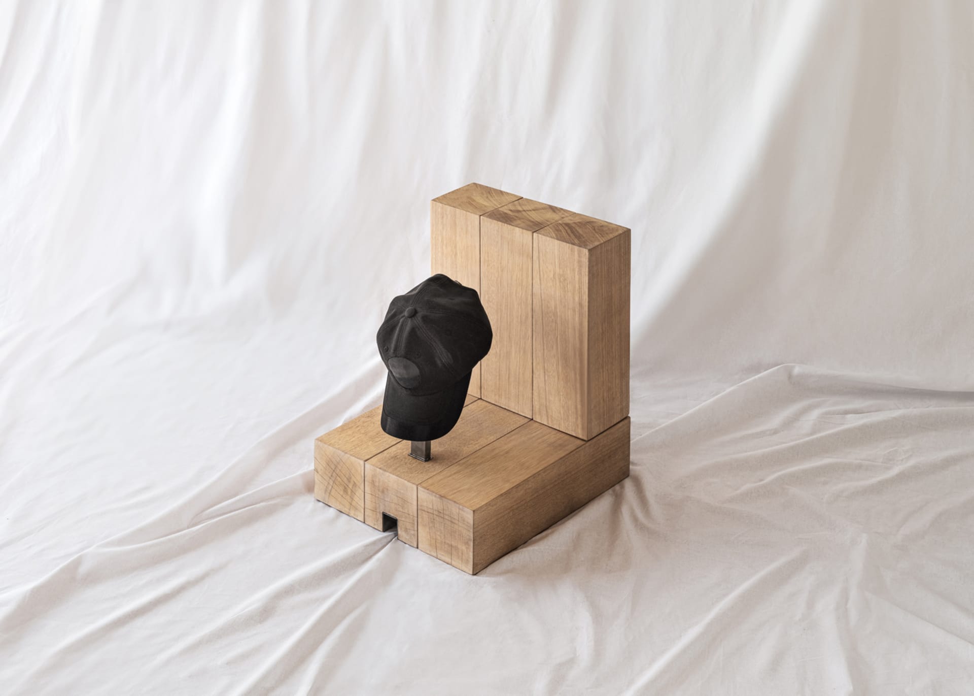 A minimalist design with a black baseball cap mounted on a wooden structure, emphasizing clean lines and simplicity.