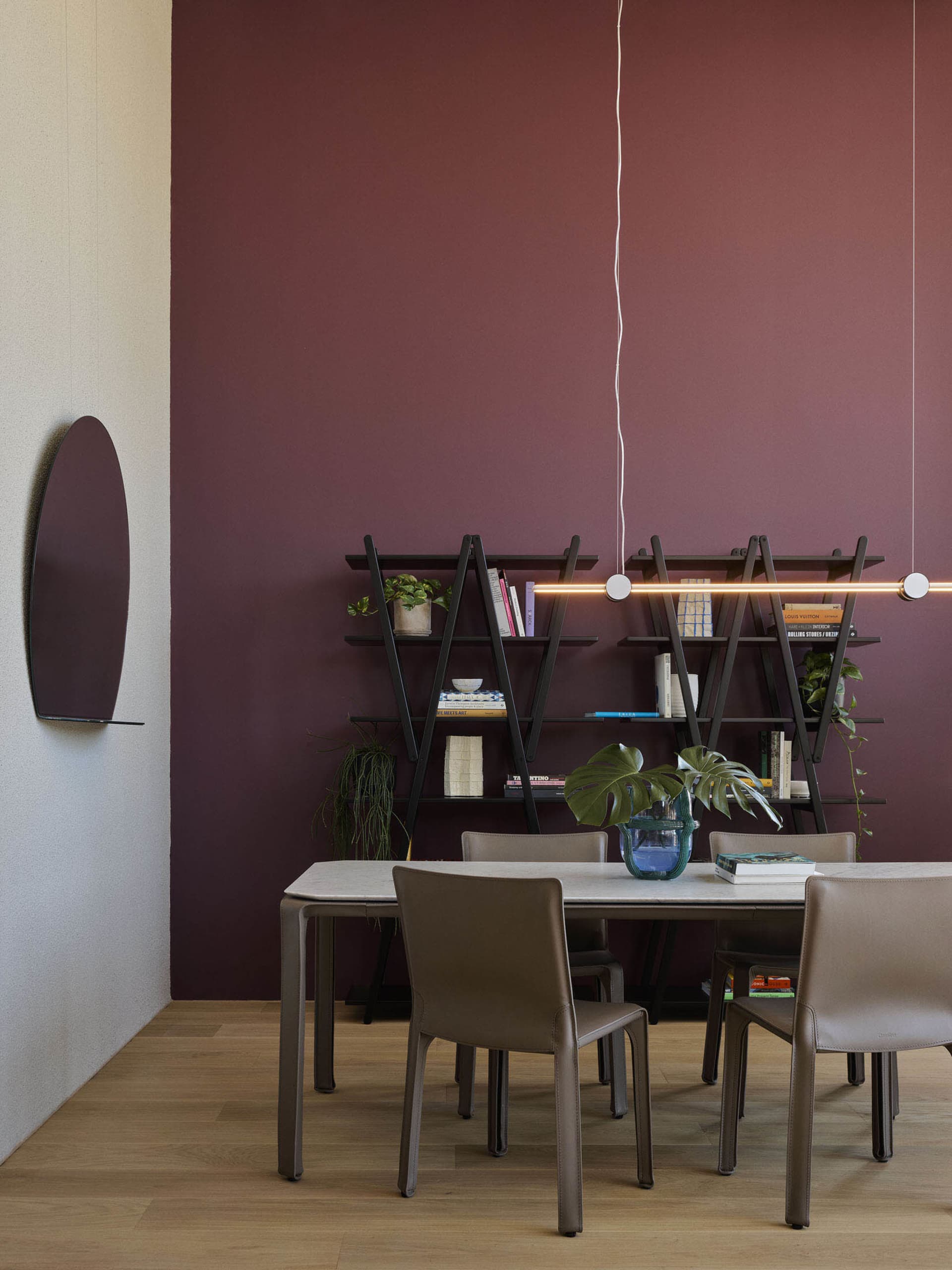 Modern dining room featuring a white table with metal legs, metal shelves, and leather chairs.