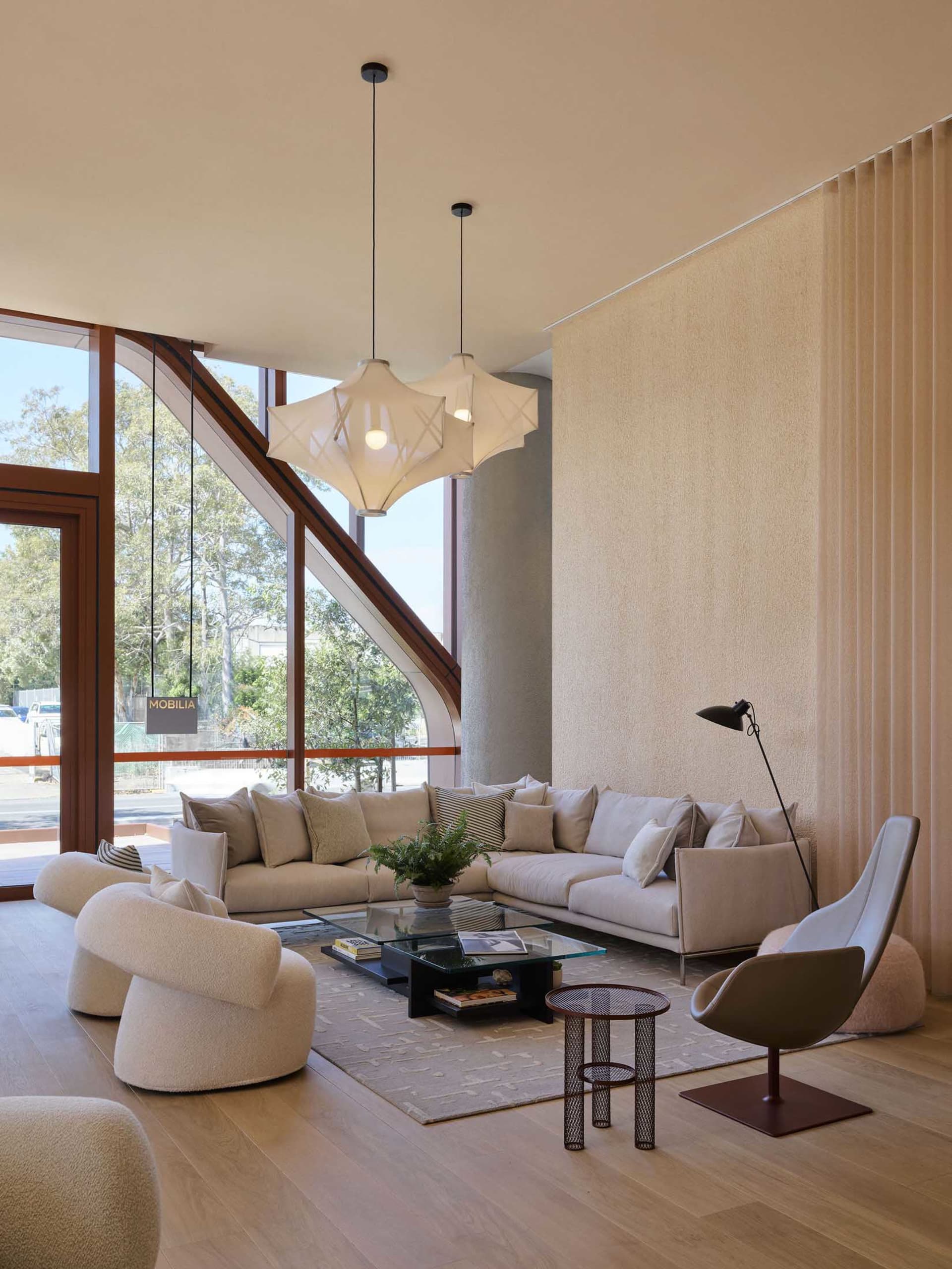 Modern living room with light-colored furniture and large windows showcasing contemporary design elements.