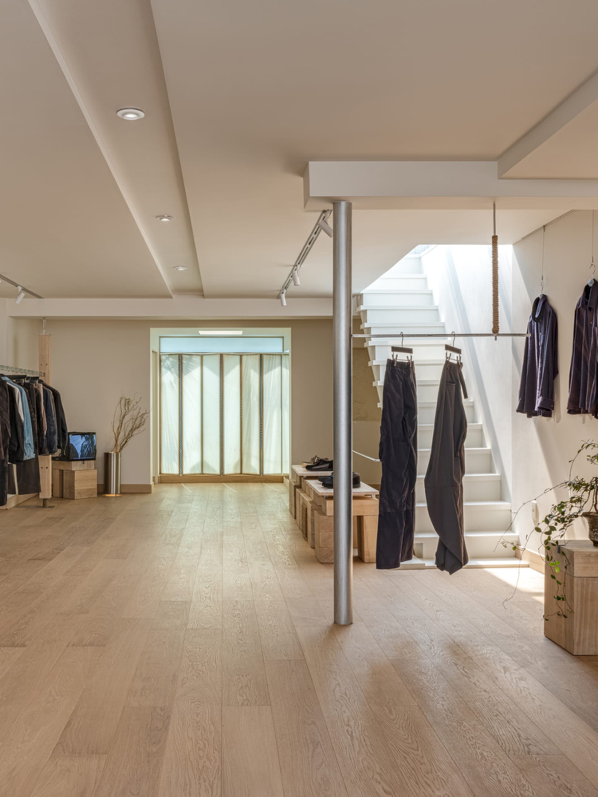 現代零售店的室內視角，展現白色木地板、白色混凝土階梯以及極簡設計。
