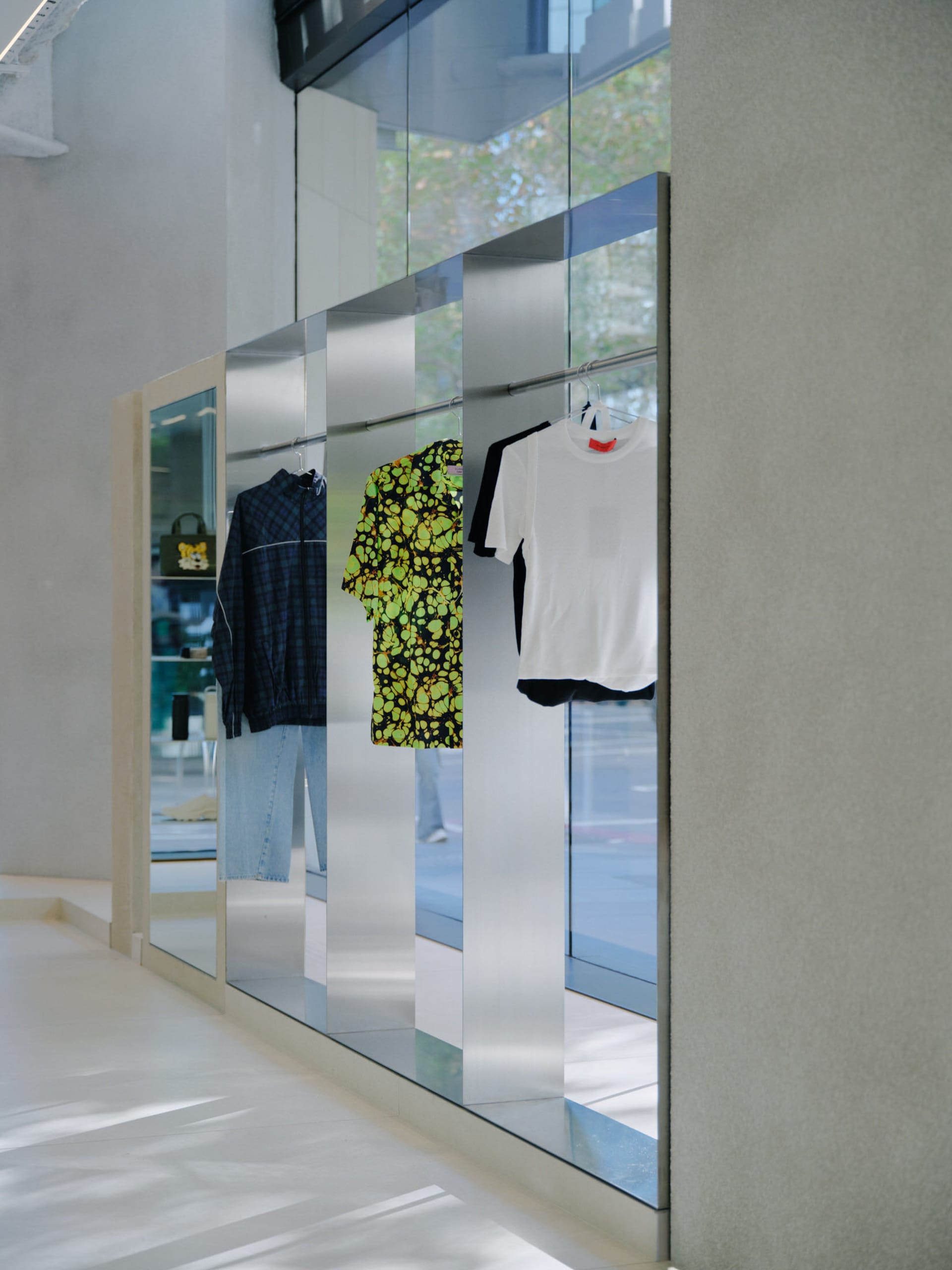 服飾店展示區陳列復古風格服飾，例如綠黃色酸性亮色襯衫與白色T恤