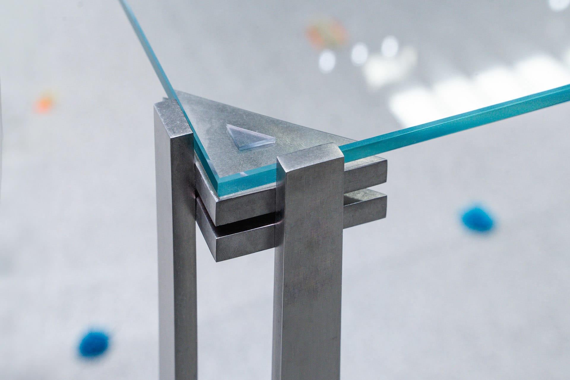A minimalist metal table with glass top and geometric design.