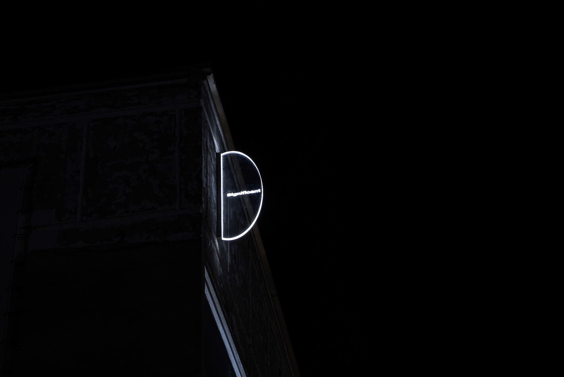 夜晚建築外牆上懸掛著發光的圓形招牌，上面寫著「Significant」。