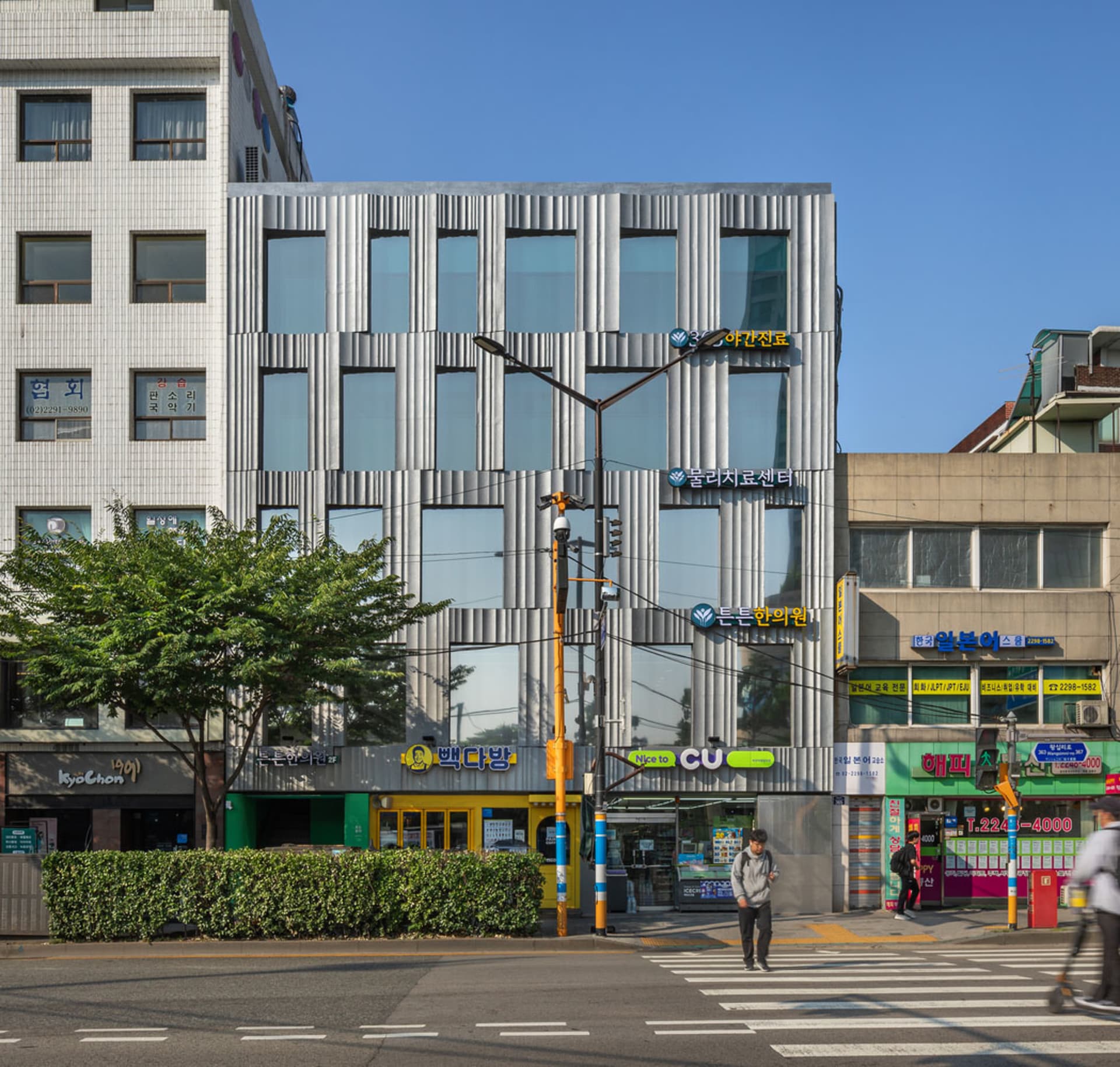 一座擁有金屬外牆板的現代辦公大樓，位於都市環境中。
