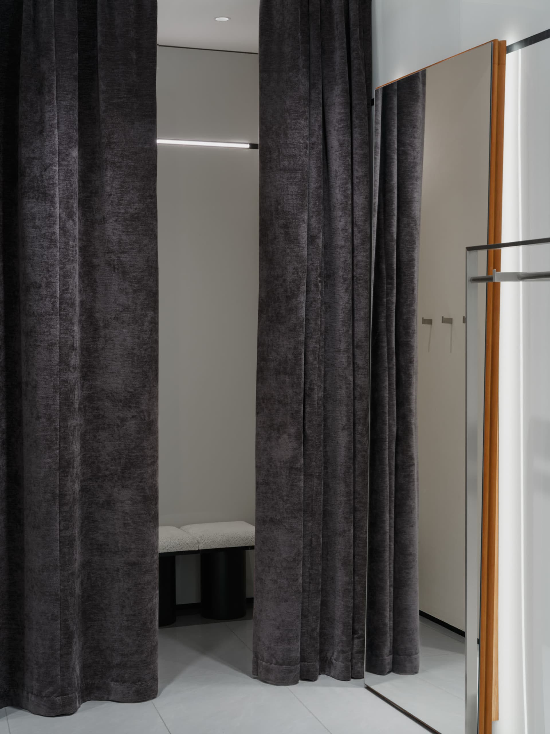 A fashion retail store with velvet curtains and a dressing room.