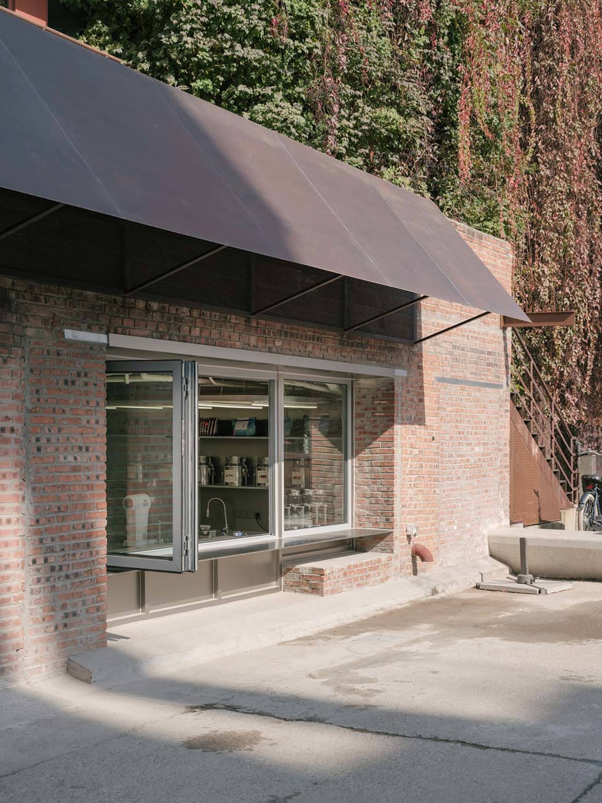 Outdoor view of a brick storefront with an open door, showcasing retail merchandise inside.