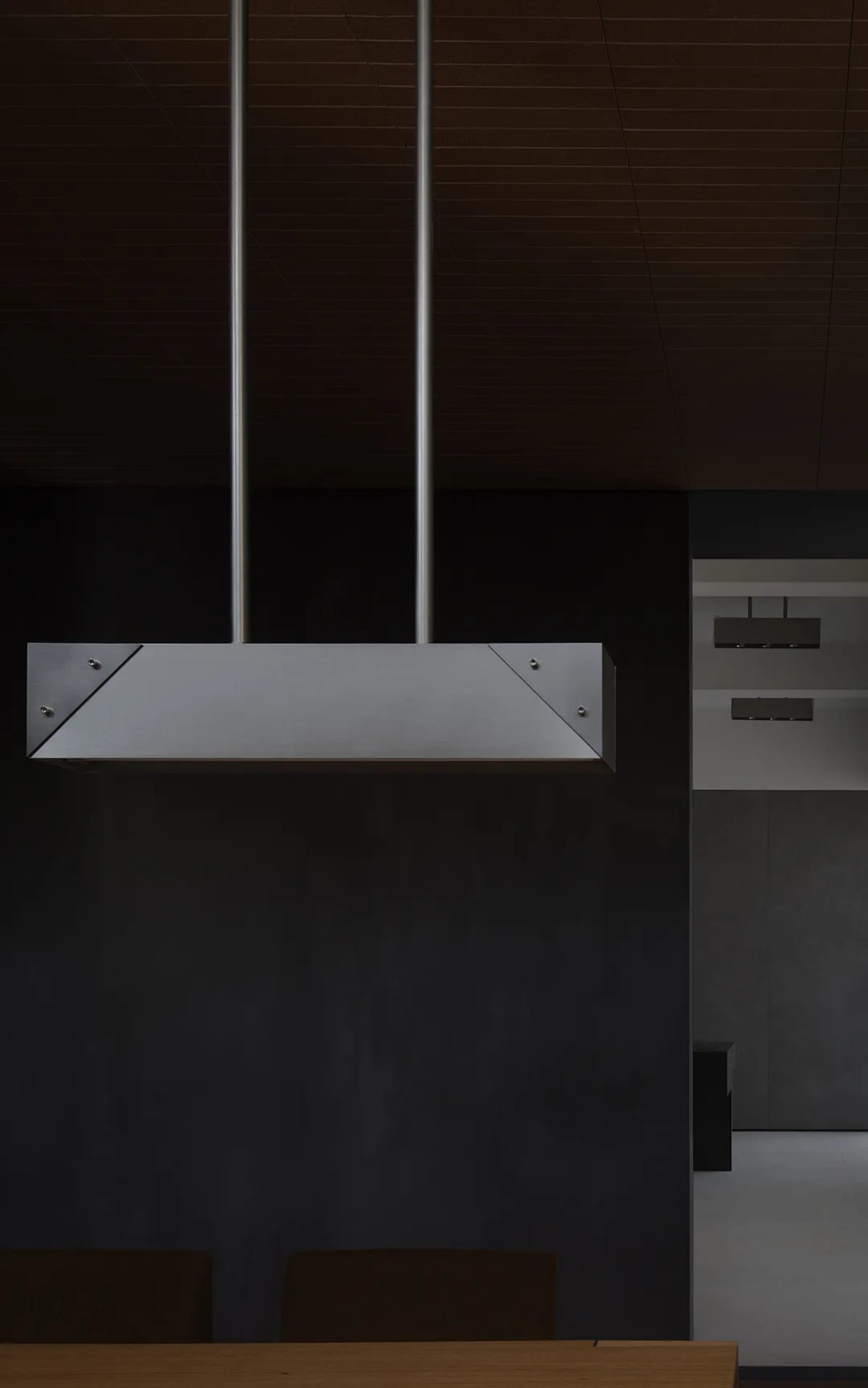 Modern kitchen interior with minimalist design, featuring metal hood and dark wood accents.