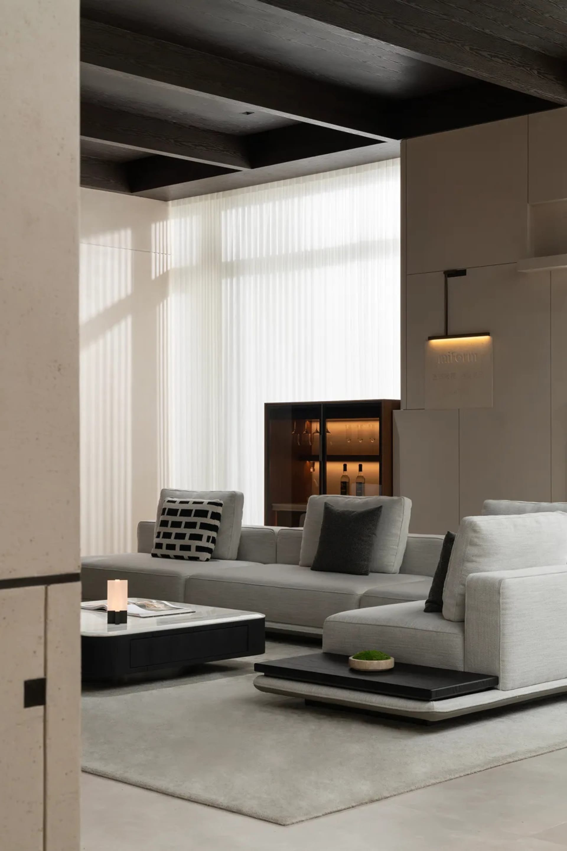 A modern living room featuring a fabric sofa with wooden accents and a chalkboard desk, illuminated by natural light through 
