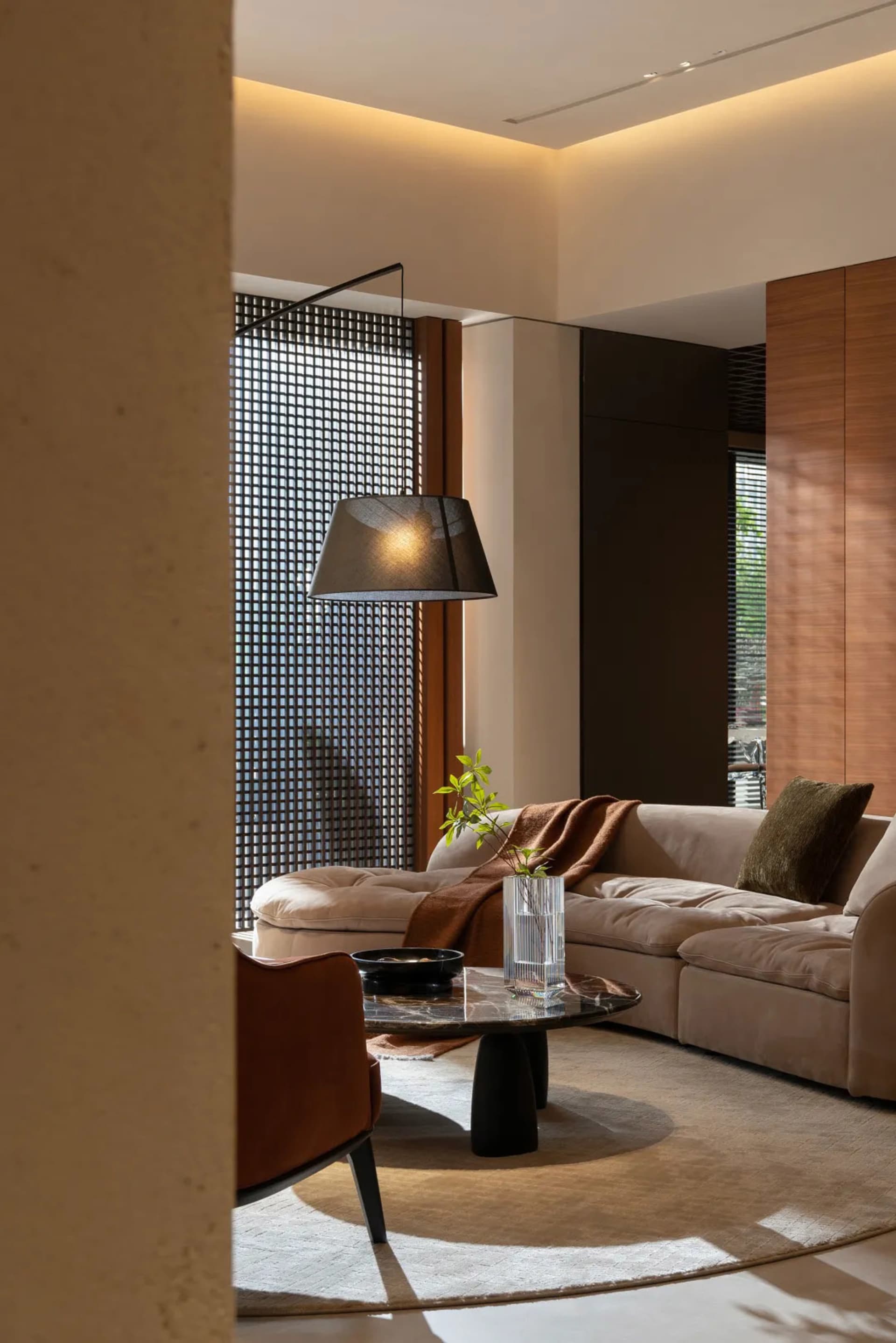 A modern living room featuring a large beige sectional sofa adorned with brown and green throw pillows, a glass liquor bowl,