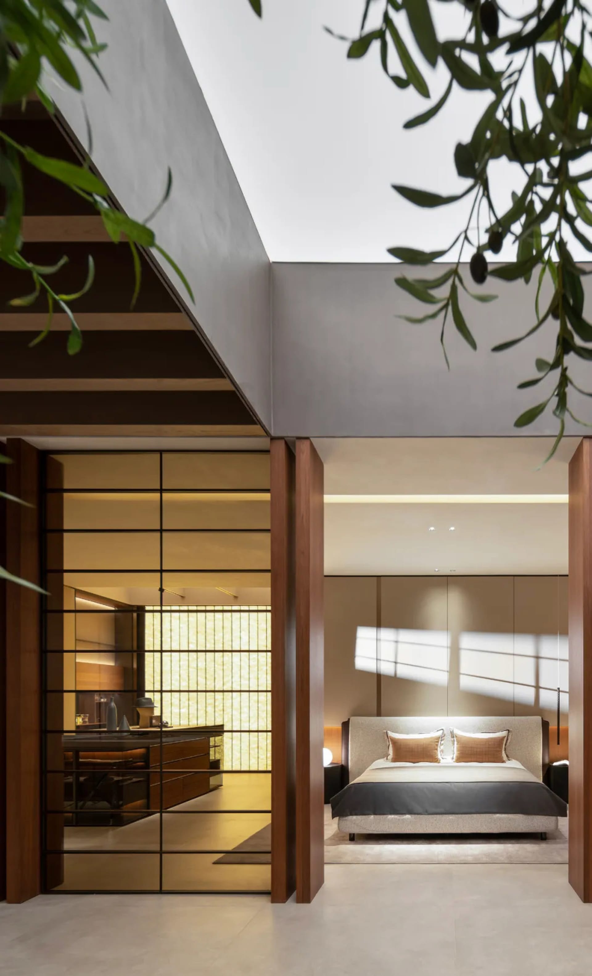 A minimalist bedroom with concrete walls and wooden furniture, featuring a large bed with upholstered headboard, desk area wi