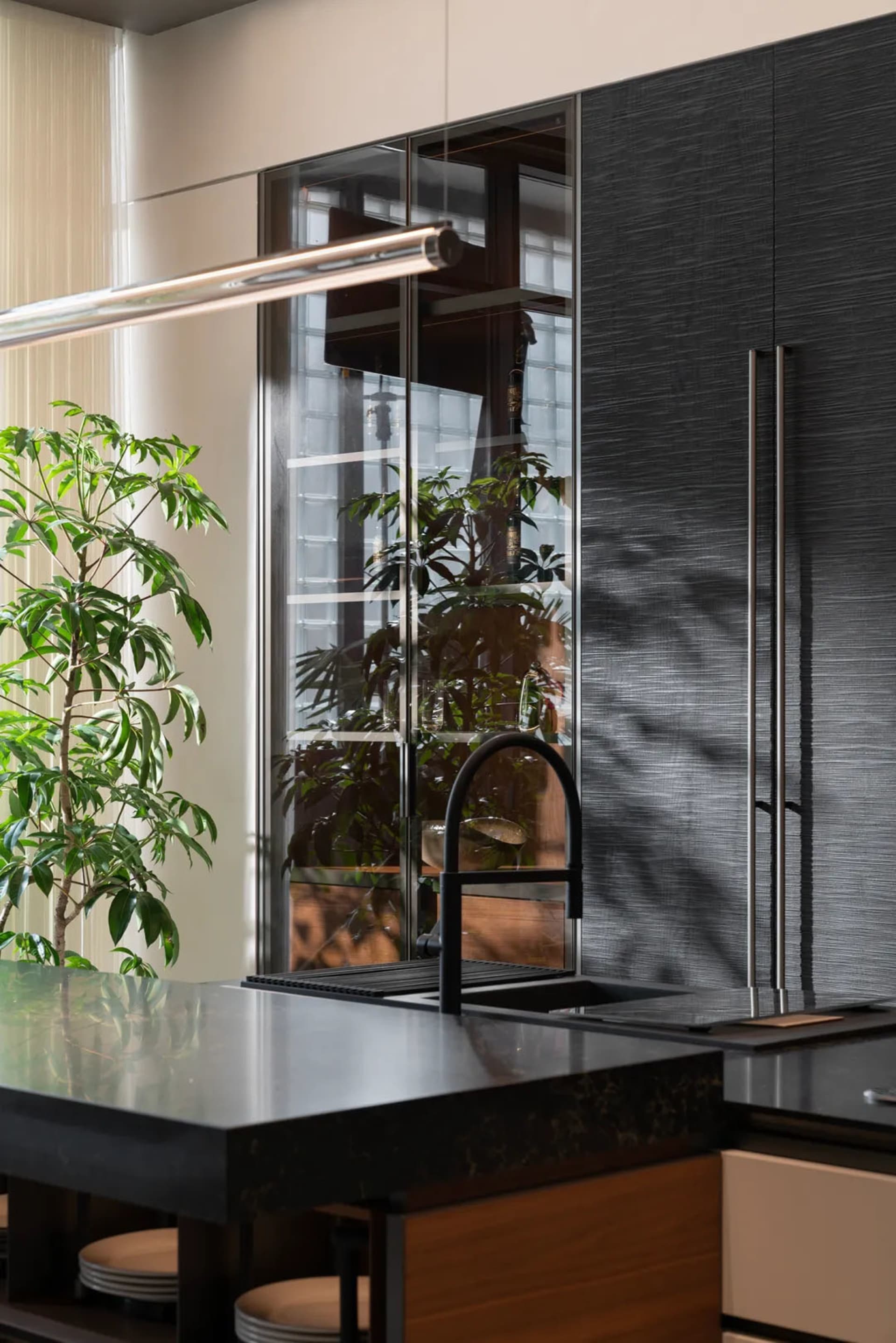 Modern residential kitchen featuring sleek black stone countertops and glass cabinetry.