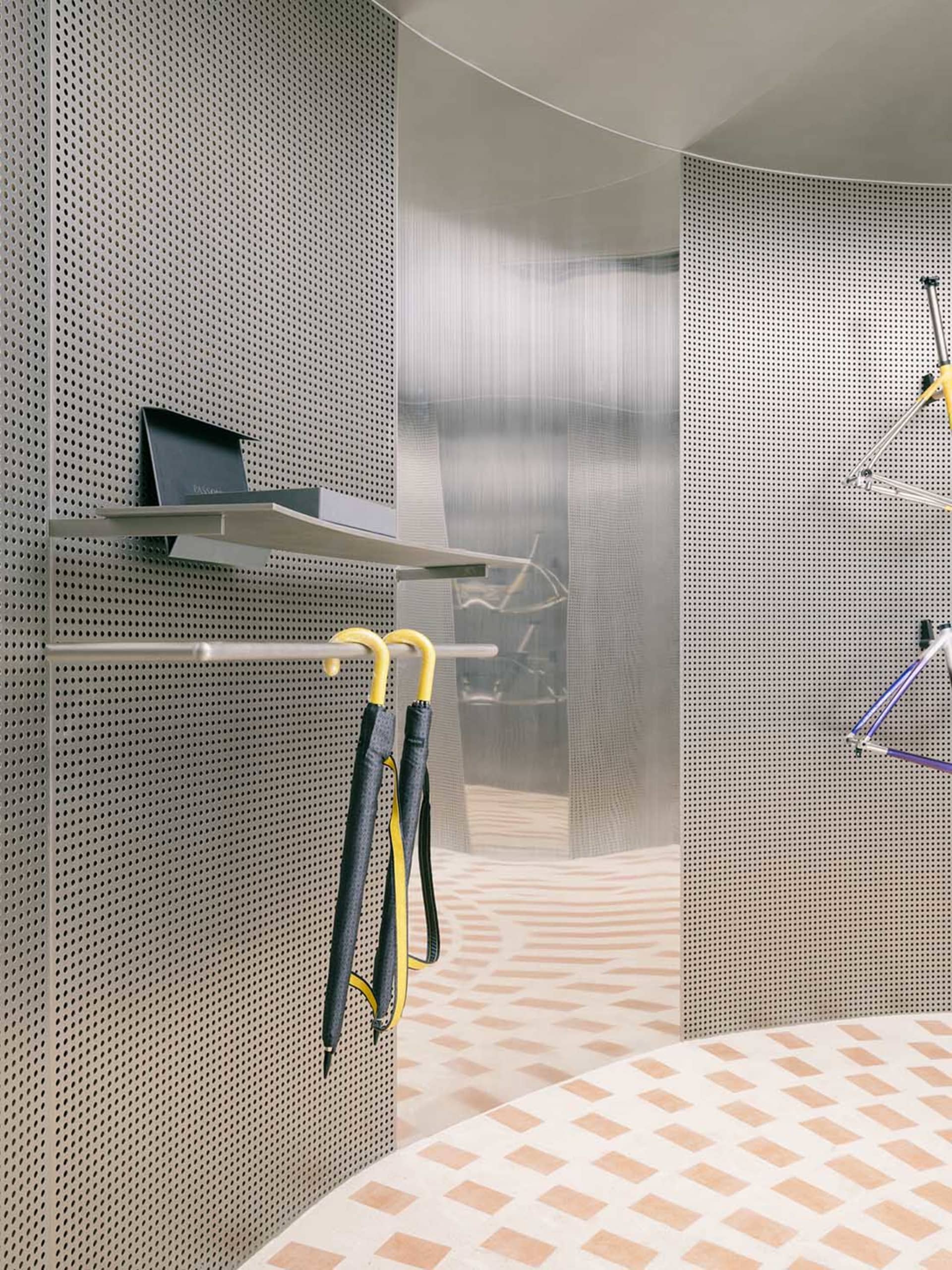 A modern interior space with perforated metal walls and a geometric floor pattern.