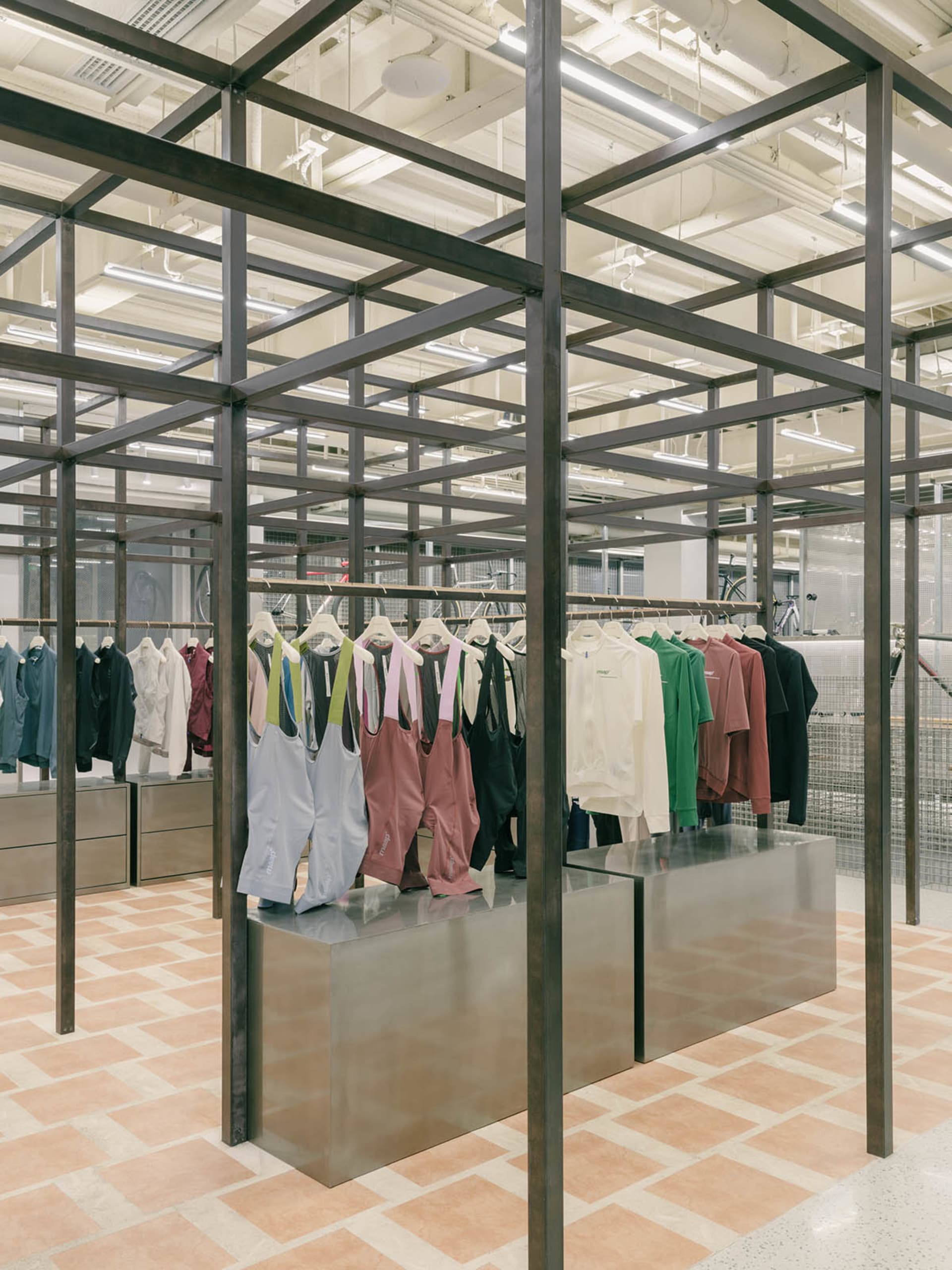 現代零售店採用金屬框架結構與混凝土地板,展示服裝商品。