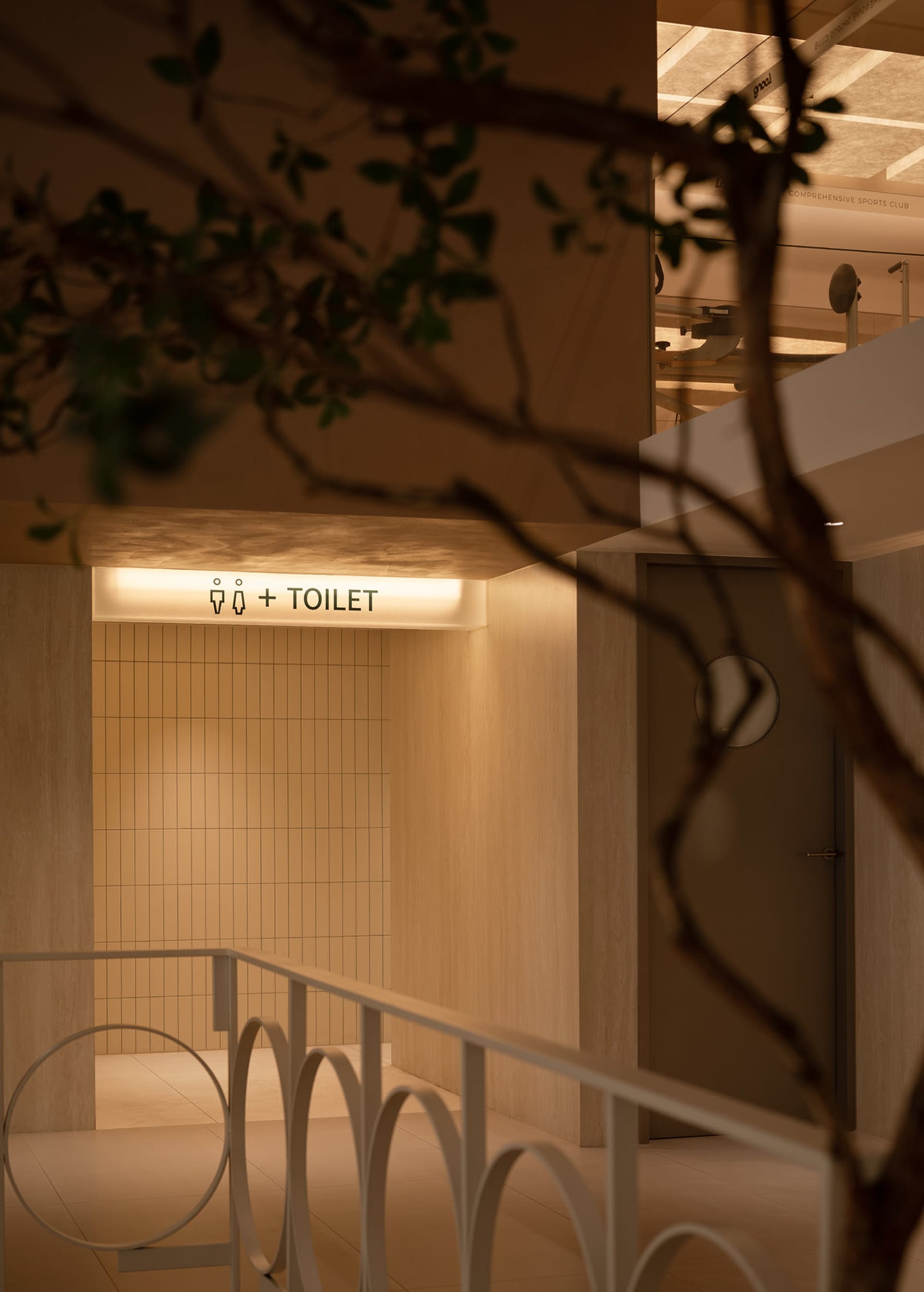 Modern public toilet with concrete walls and tiled floor, featuring a illuminated entrance sign.