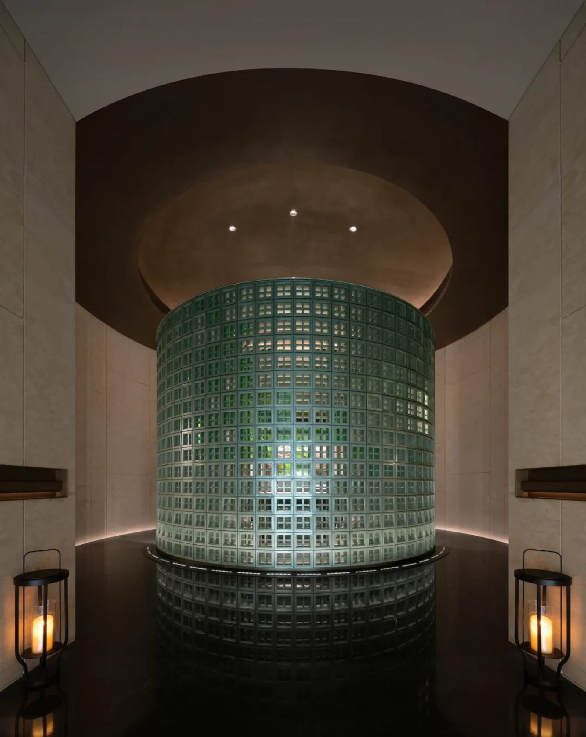 A modern spa interior with a cylindrical glass block wall, illuminated from within.