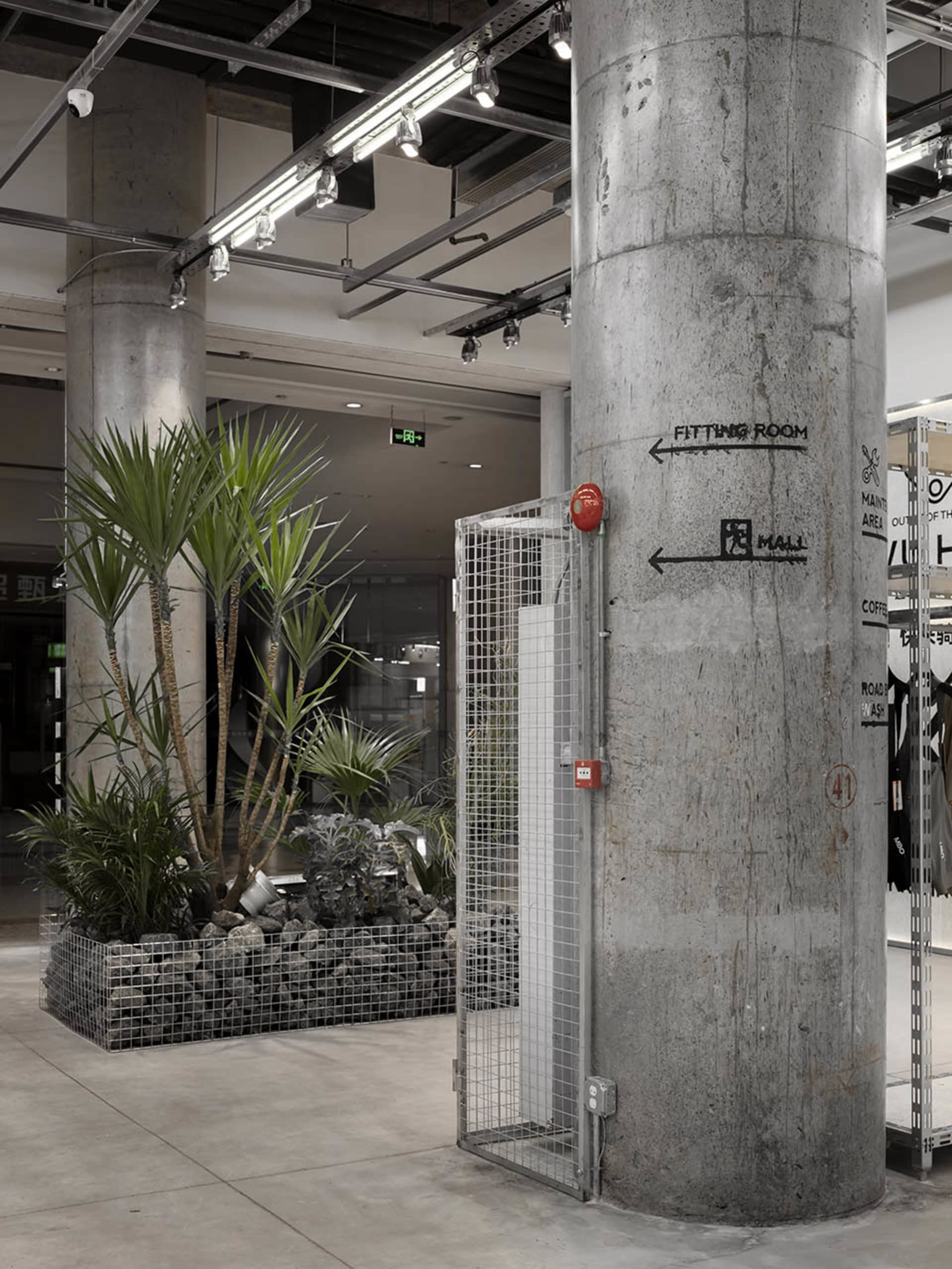 工業風店面，展示混凝土柱與綠意植栽的現代設計