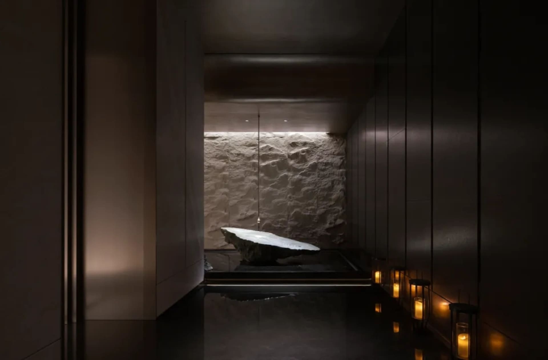 A minimalist spa room featuring concrete walls and illuminated candles.