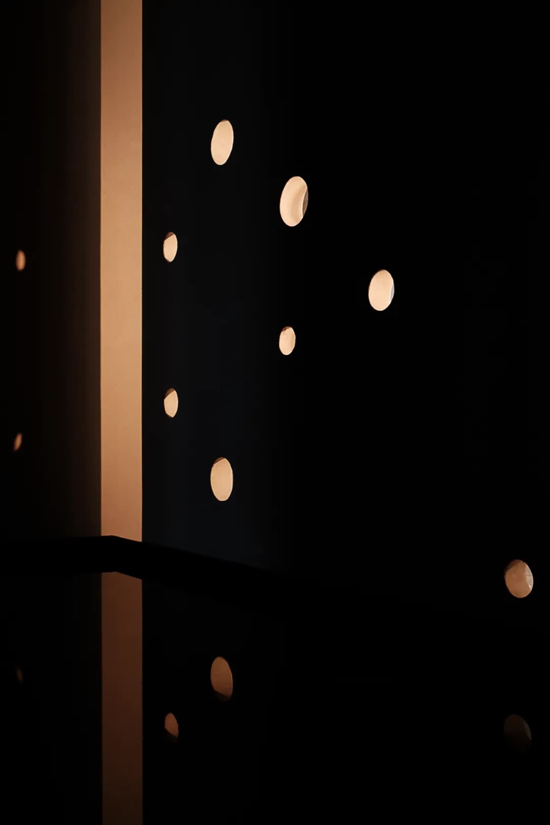Minimalist interior design featuring illuminated circular lights reflected in a polished surface.